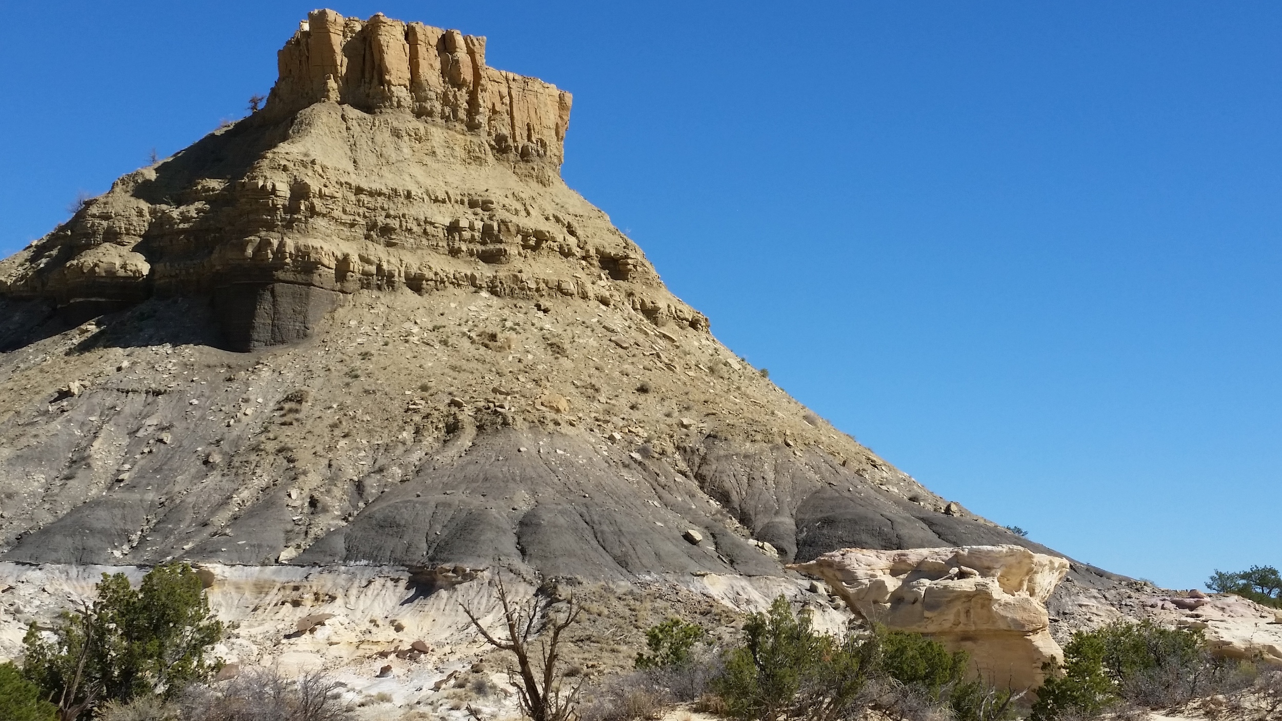  A butte of bentonite hills with a sandstone cap. 