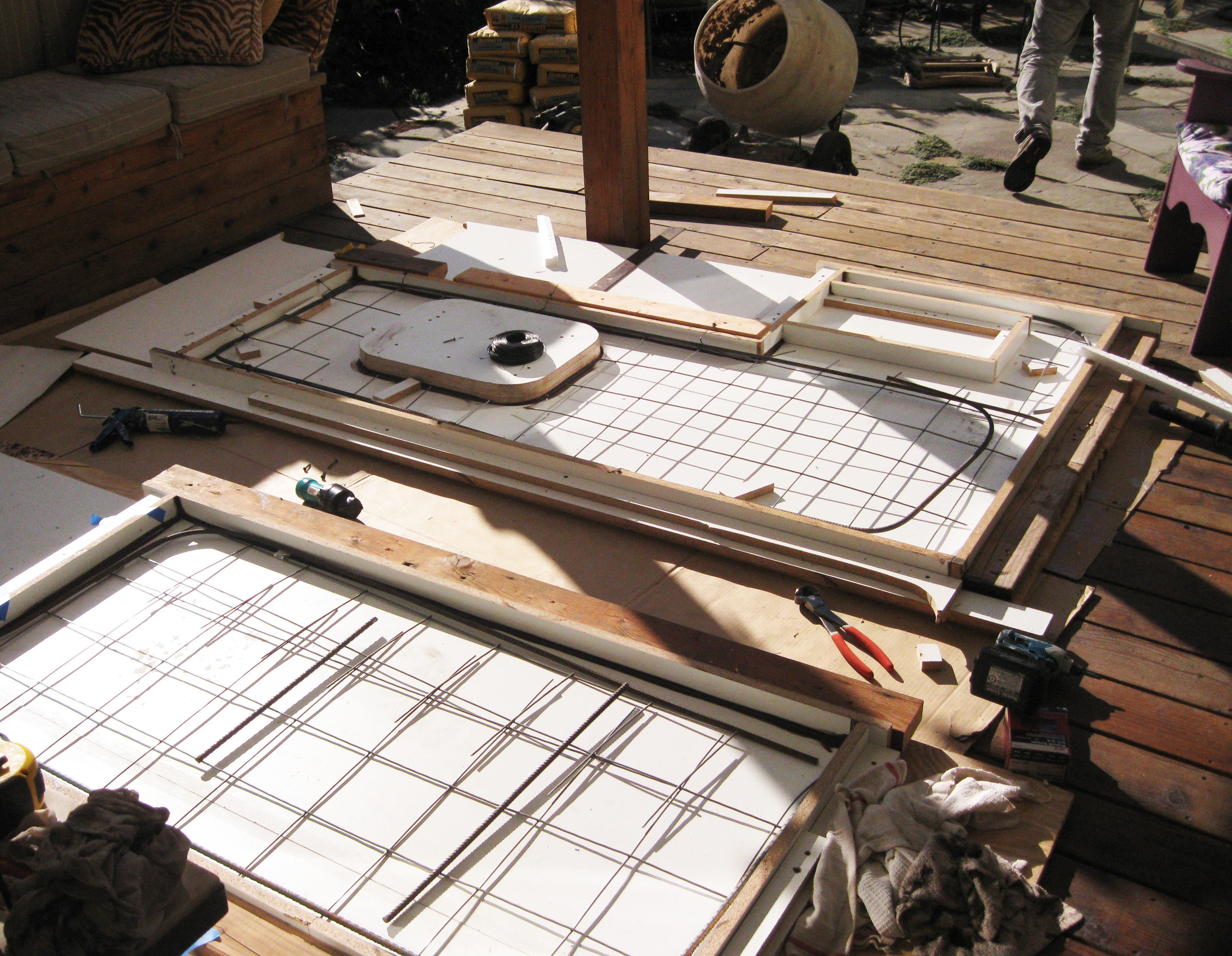 Concrete counter tops are poured upside down and formed using sheets of melamine. Shown here are two sections of the counter top with welded wire mesh reinforcement. In the top section you can see the cut-outs for the sink and burner insert.