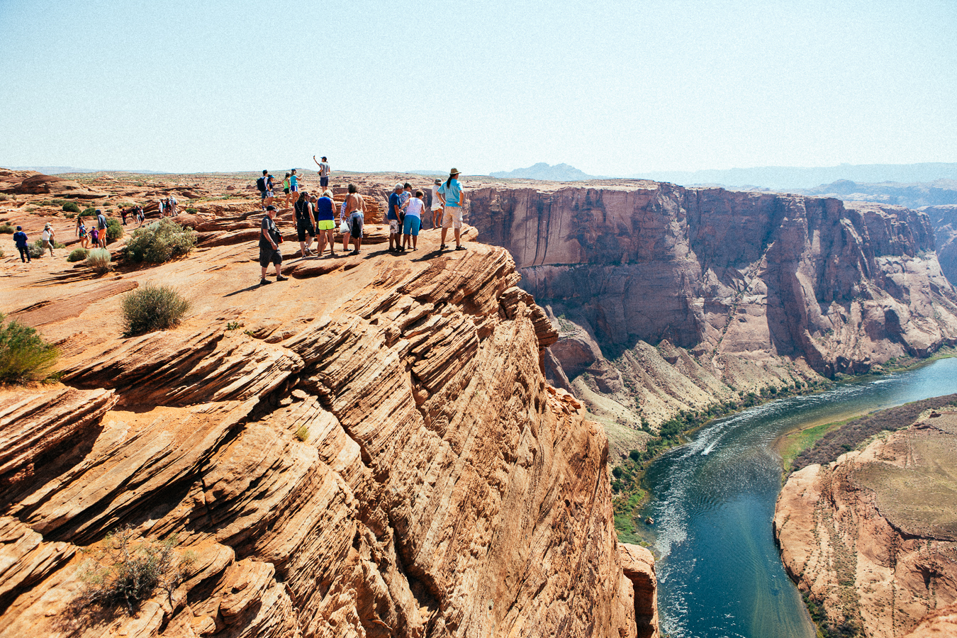 Near Lake Powell is a point where the Colorado River wraps a 270º curve, called Horseshoe Bend. It's a fairly easy hike to view it, which brings hundreds of tourists to this 1000' cliff where you can get right near the edge...