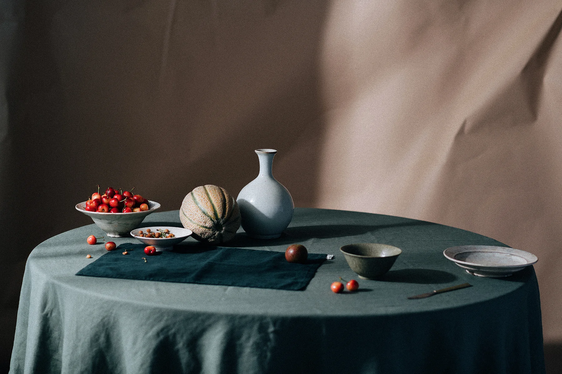 Still life photograph for In Bed Linen editorial studio featuring fruit and pottery on a tabletop