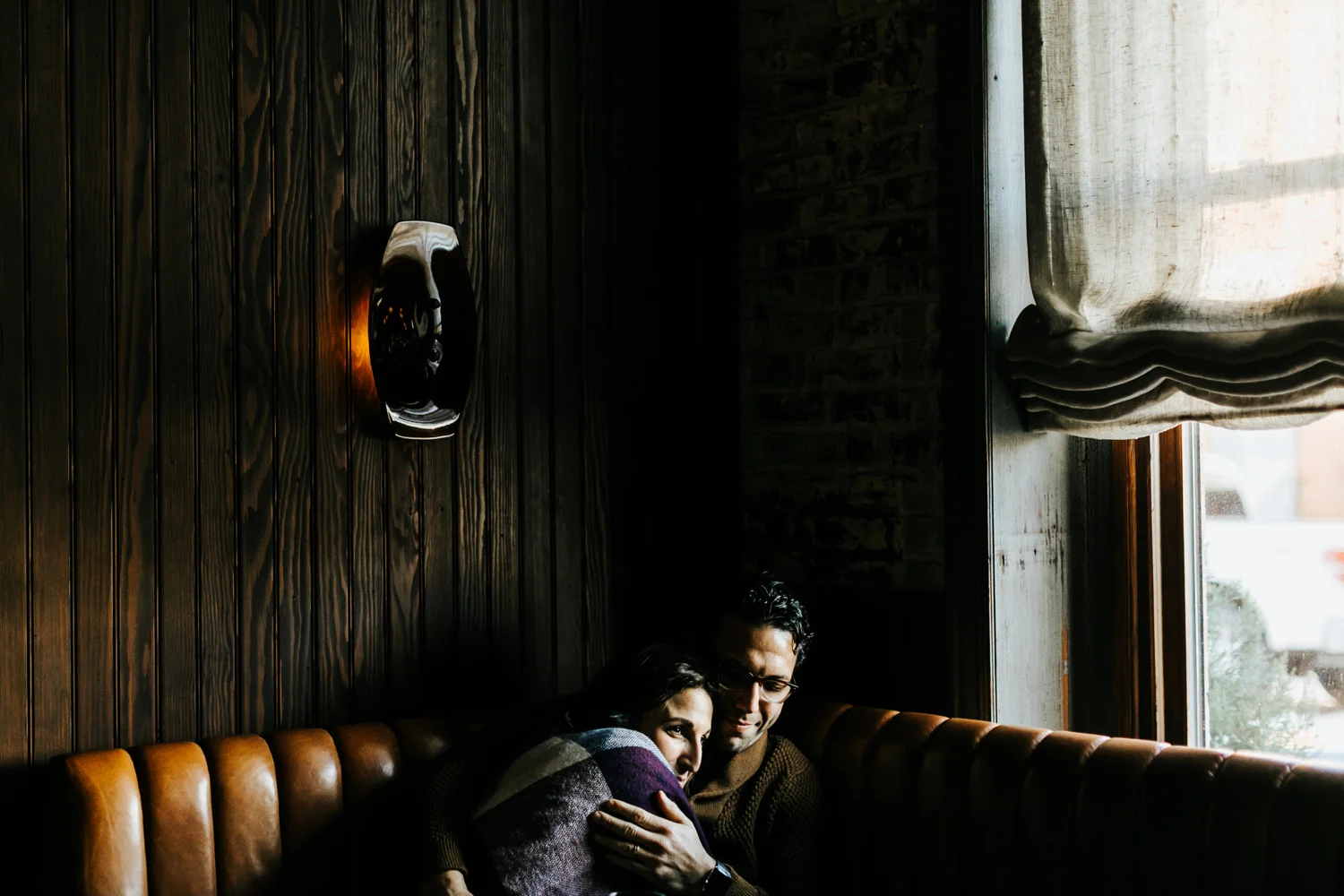 A couple holding each other sitting down in a restaurant