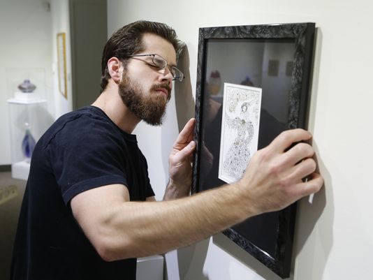 Michael Crowthers carefully hangs a pen, ink and 23K gold work titled "The Muse" by artist Ilana Debikey Monday, December 14, 2015, at the Art Museum of Greater Lafayette. Crowthers is Curator of Collections Exhibitions and Education.(Photo: John Terhune/Journal & Courier)