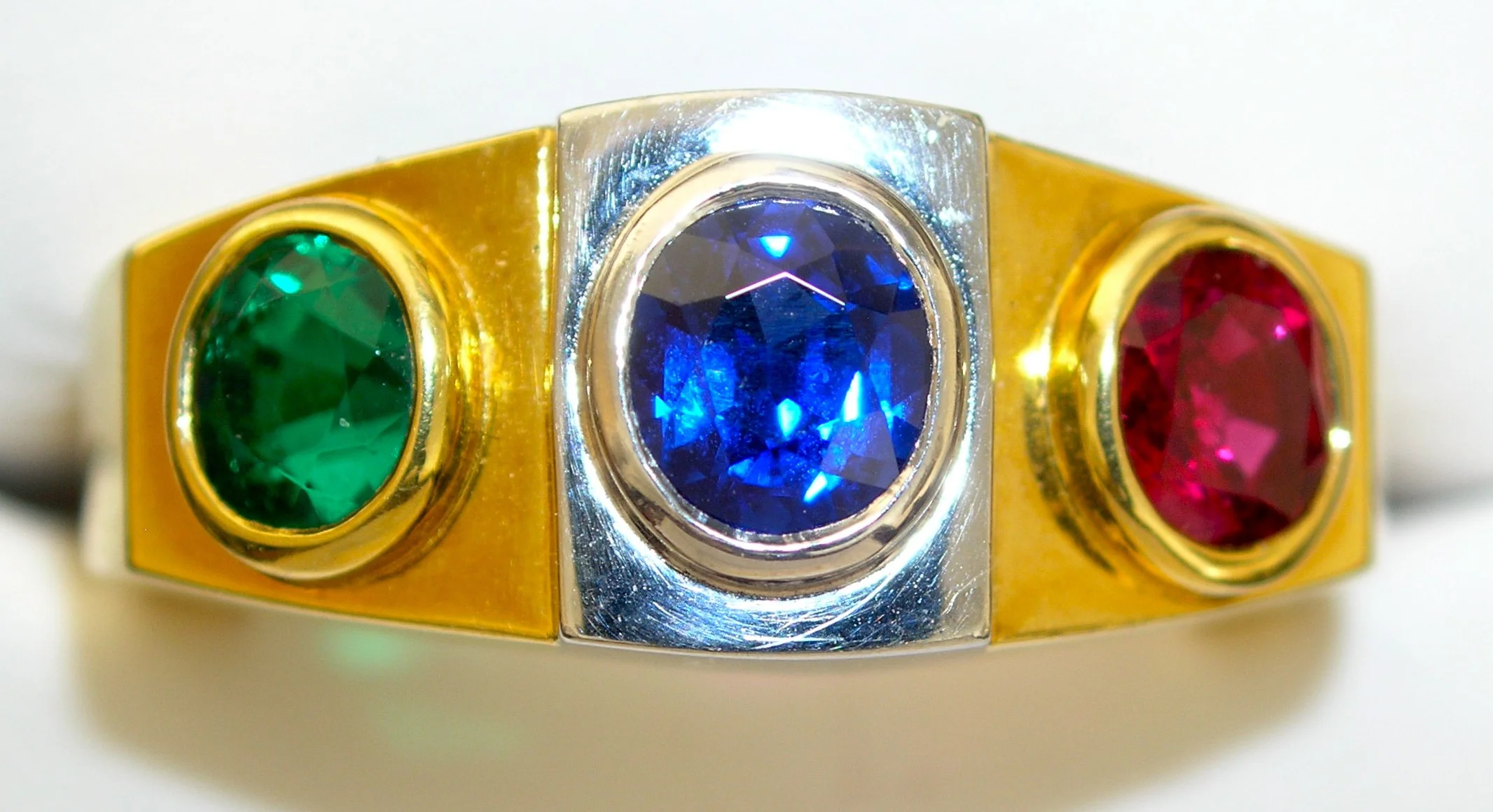 The late master cutter & gem trader Reginald Miller wore this "trip ring" to serve as his color guide on his trips to the world's gem producing capitals from 1951-1988. This Colombian emerald, Burma sapphire, and Burma ruby served as his benchmark for the finest. 