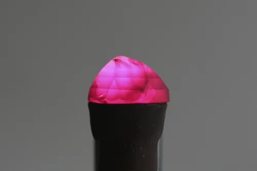 A 21 Carat historic ruby illuminated by a fiber optic light while on the dop stick just after being re-cut by Jerrold Green of the Reginald C. Miller lapidary. 
