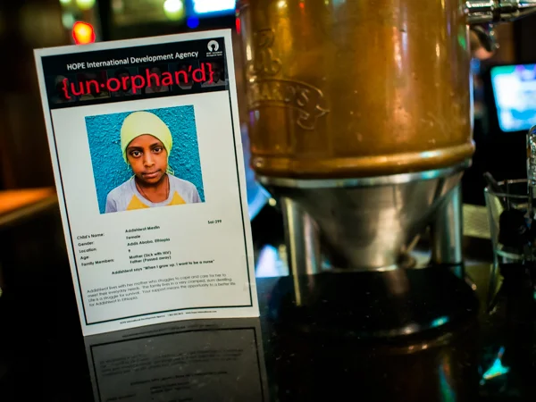 "Un-orphan'd" say the leaflets with photographs of the children orphaned by AIDS in Ethiopia. At HOPE International Development Agency fundraising event at The Blarney Stone Pub, Vancouver, BC, Canada on November 3, 2013.