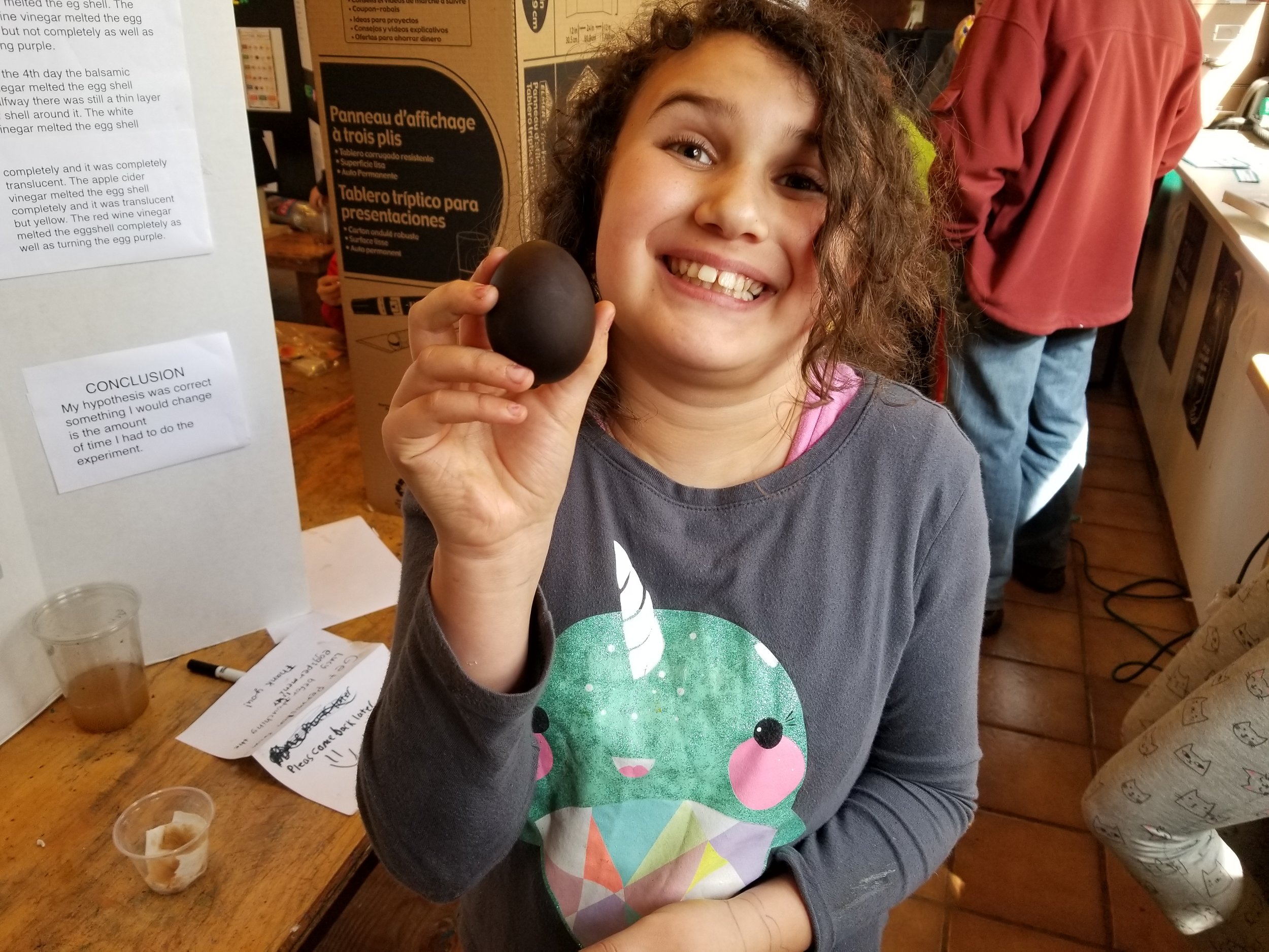 Lucy shows off one of her test subject vinegar eggs (the shell dissolves leaving only the membrane). This one was in balsamic vinegar which is why it is black.