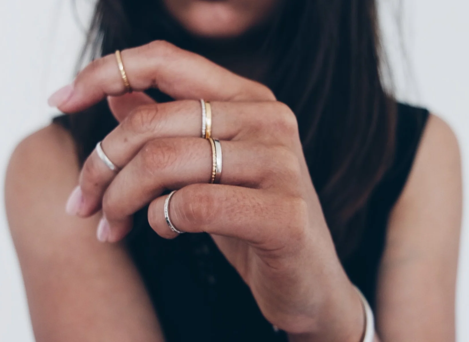 woman's hand wearing gold and silver battered rings