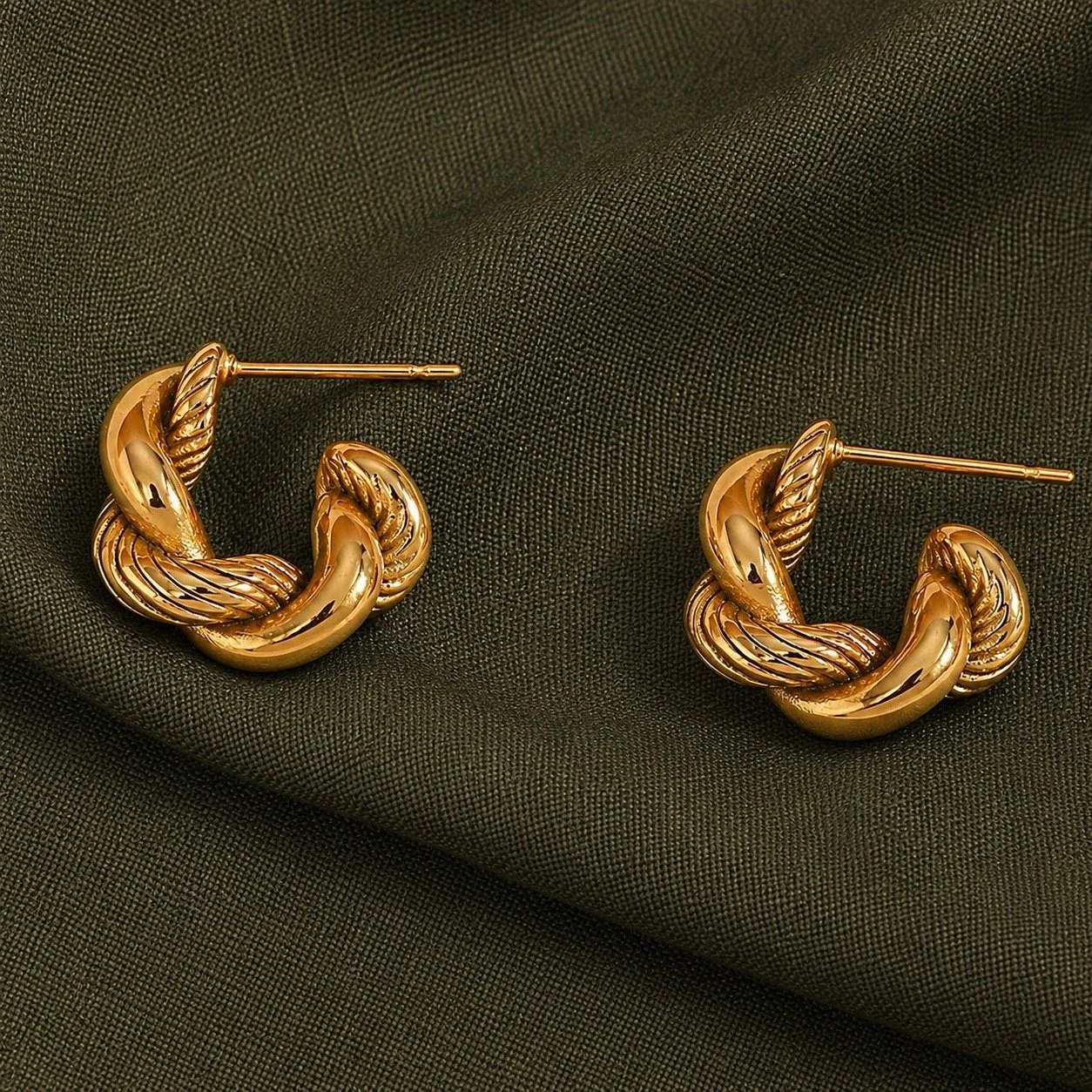 House Thirteen Twisted Knot Hoop Earrings styled on sage green fabric, chunky gold twisted rope hoop earrings