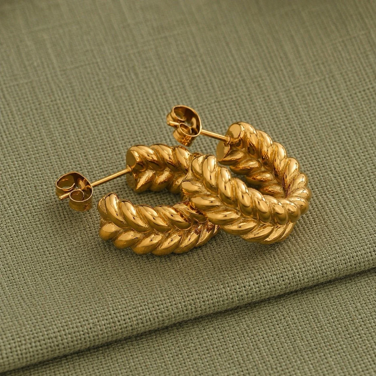 House Thirteen Chunky Braided Hoop Earrings on sage green fabric showing braided detail, tarnish resistant gold stainless steel hoops