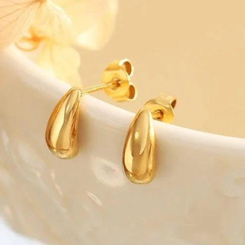 ouse Thirteen Teardrop Stud Earrings resting on white ceramic dish with dried flowers, waterproof gold drop stud earrings