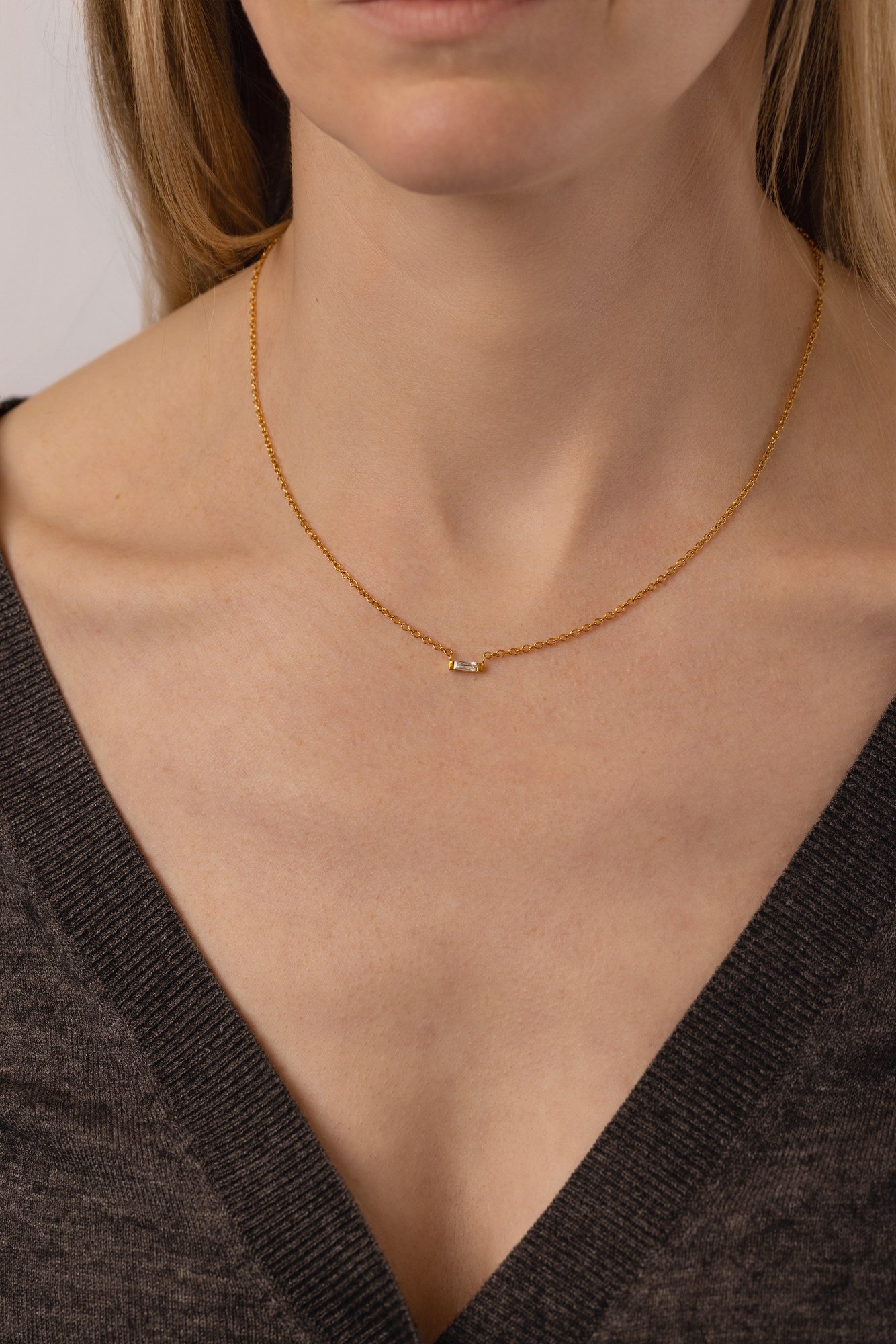 House Thirteen Baguette Necklace worn on model. A small CZ baguette in a gold pendant on cable chain. Dainty and wearable jewellery