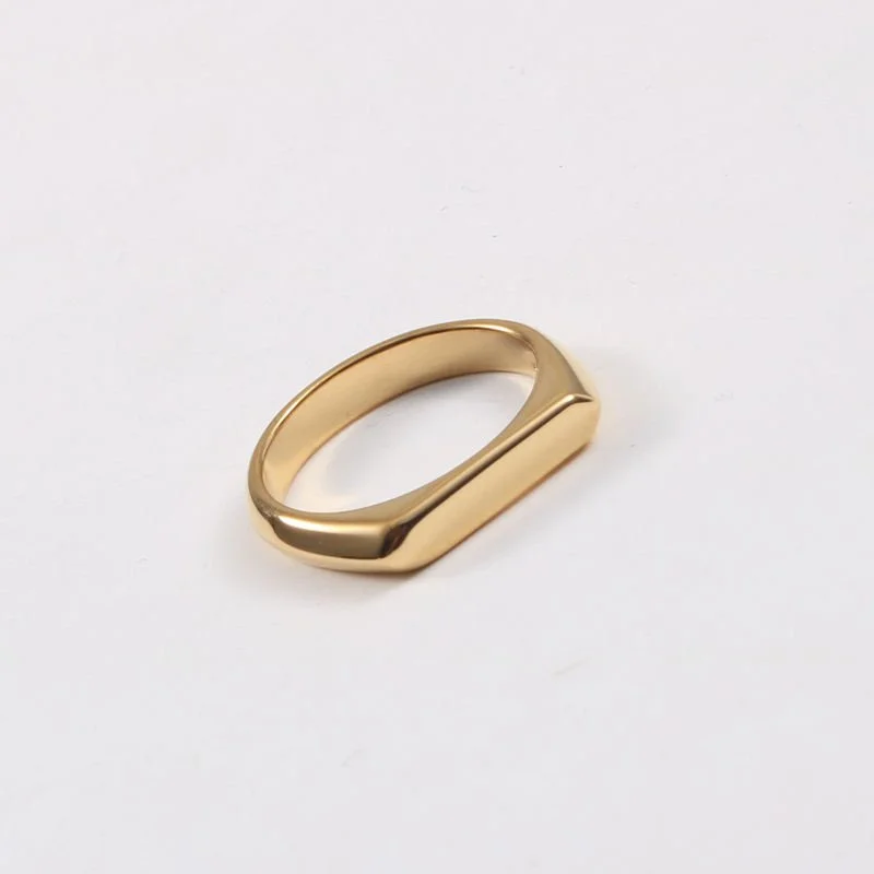 Slim gold signet ring with elongated oval face photographed on white background