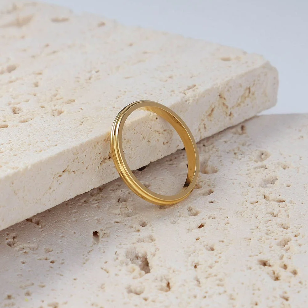 House Thirteen Ridge Stacking Ring in gold styled upright on neutral travertine stones. Stackable ridged gold band with a minimalistic feel