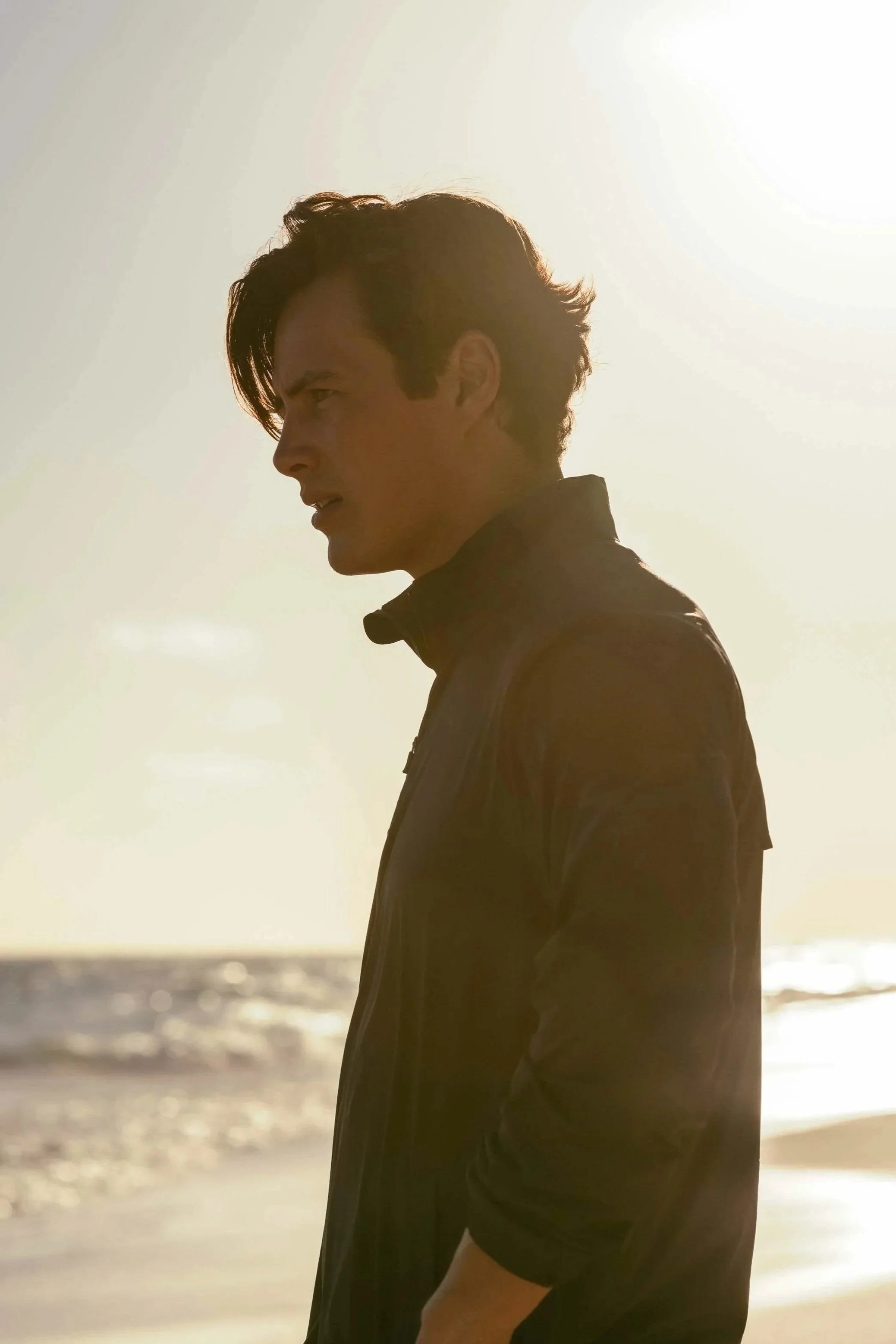 Model Harry Gozzett stands on beach backlit by the sun - Southern Tide campaign photographed by Scott Wild