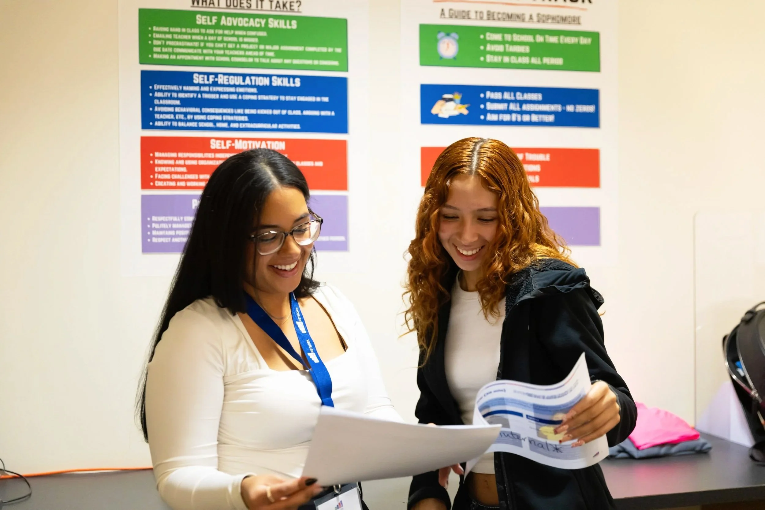 A teacher and a high school student looking at a report and smiling