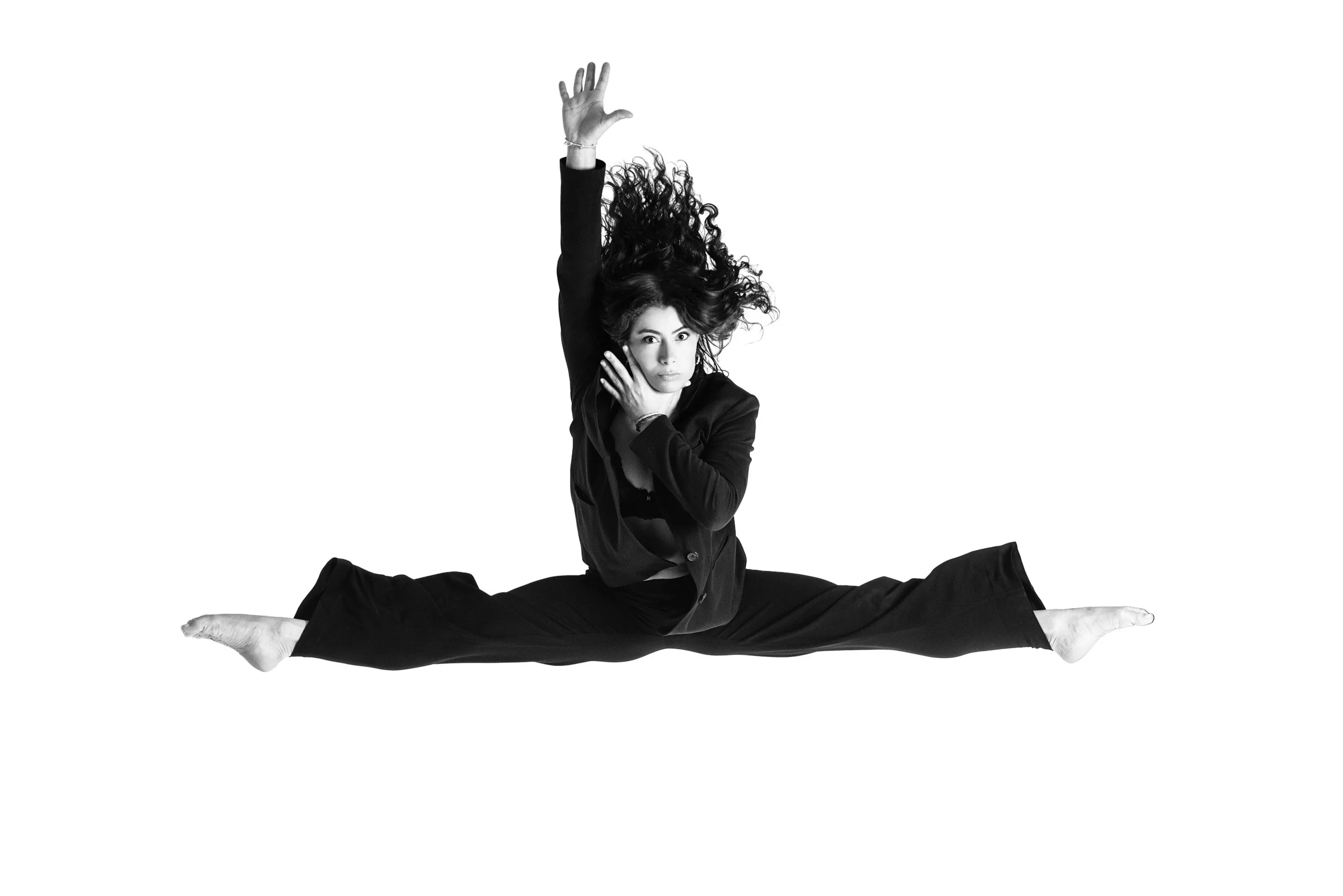A dancer suspended midair in a clean black-and-white studio portrait. The moment captures height, control, and precision, freezing motion at its peak.