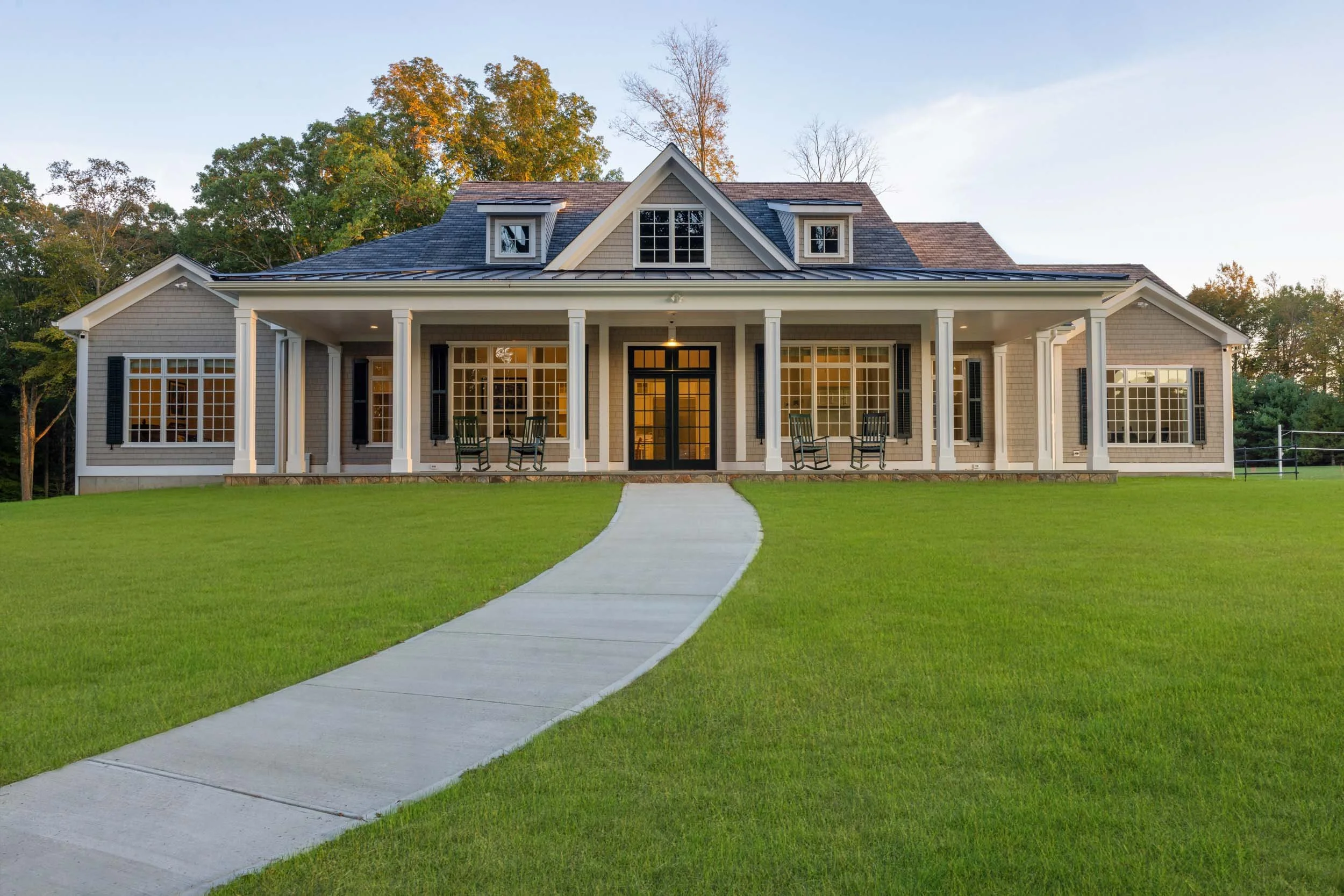 Front exterior of single-family home with covered porch and landscaped lawn photographed in Connecticut