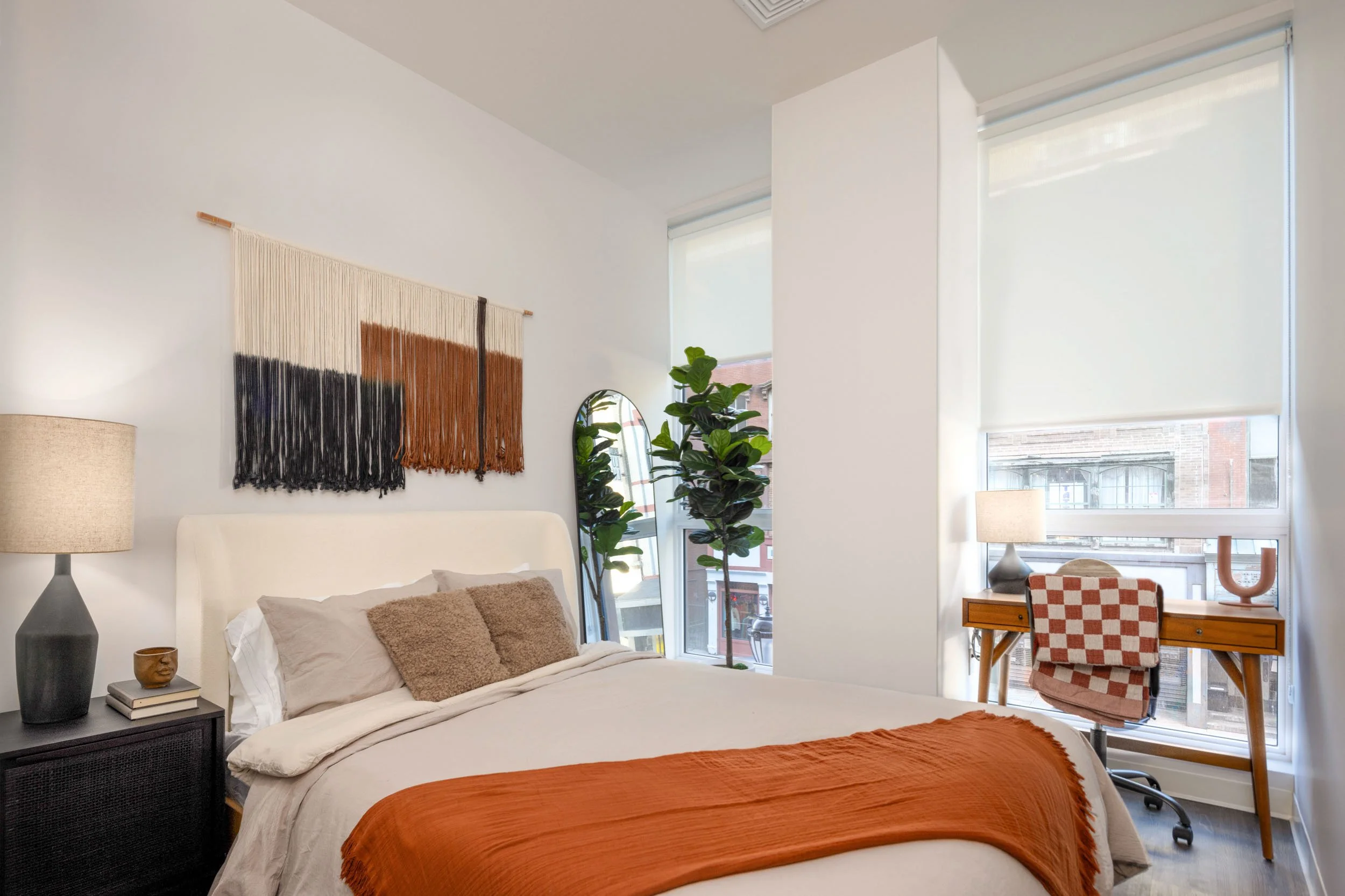 Bright residential bedroom with neutral bedding, modern decor, and large windows photographed in a Connecticut luxury apartment