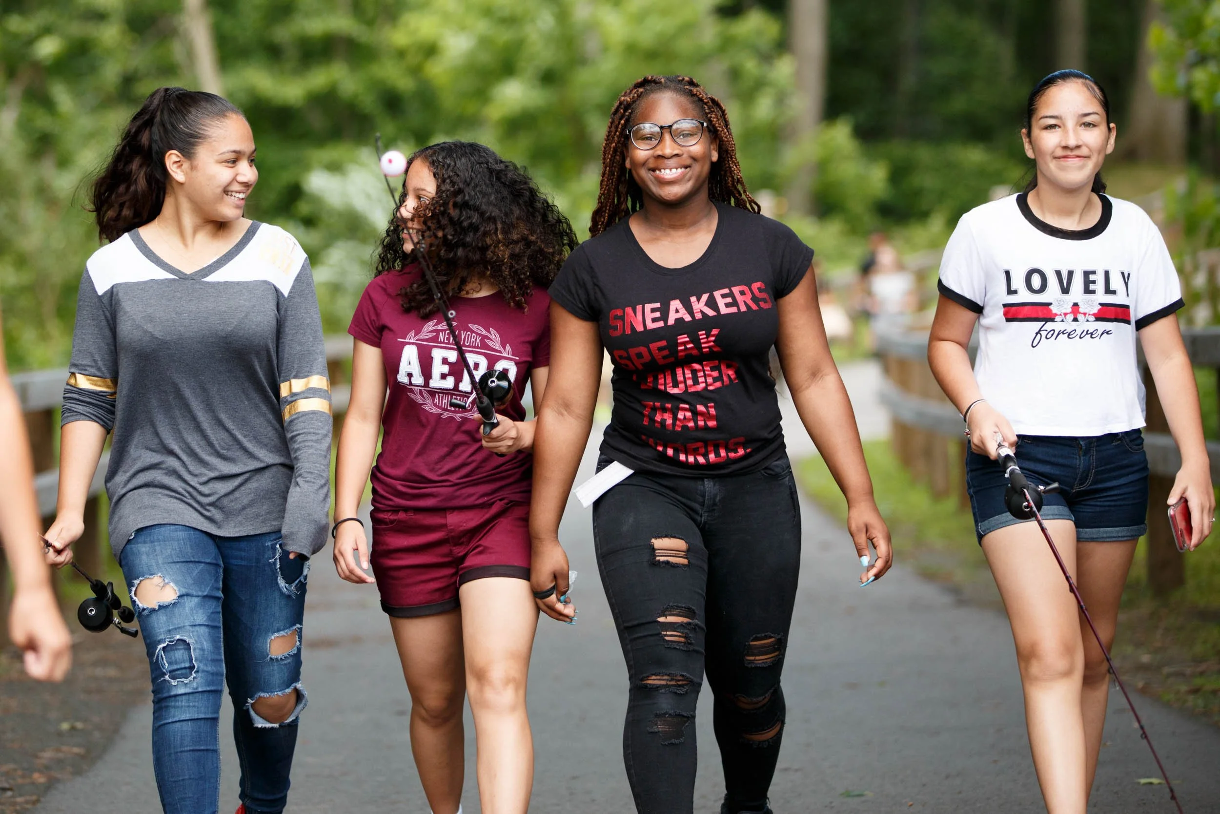 four high school female students walking down a path towards the camera