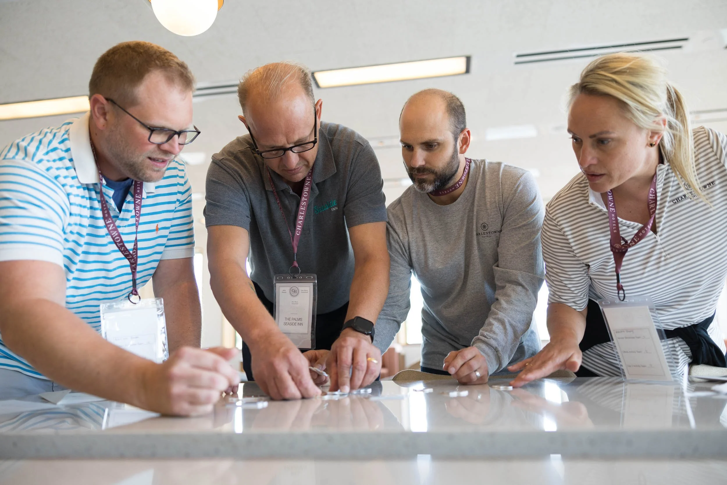 Four corporate workers from Charlestown Hotels  hunched over a table working on a puzzle