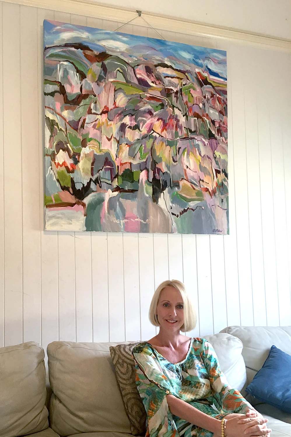 Alison in her West End home in Brisbane with her commissioned abstract landscape painting