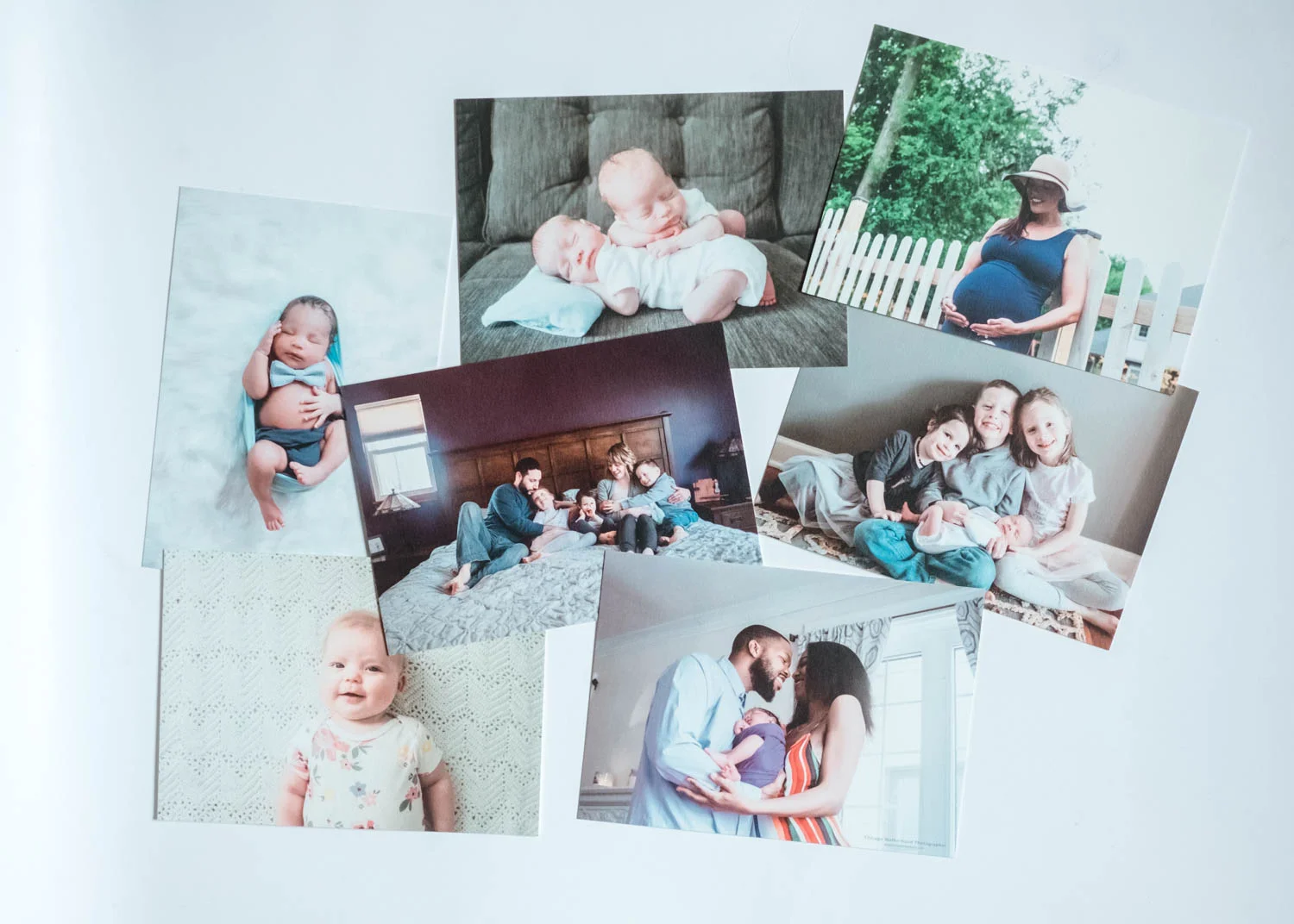 A collection of printed photographs featuring babies, children, families, and a pregnant woman.