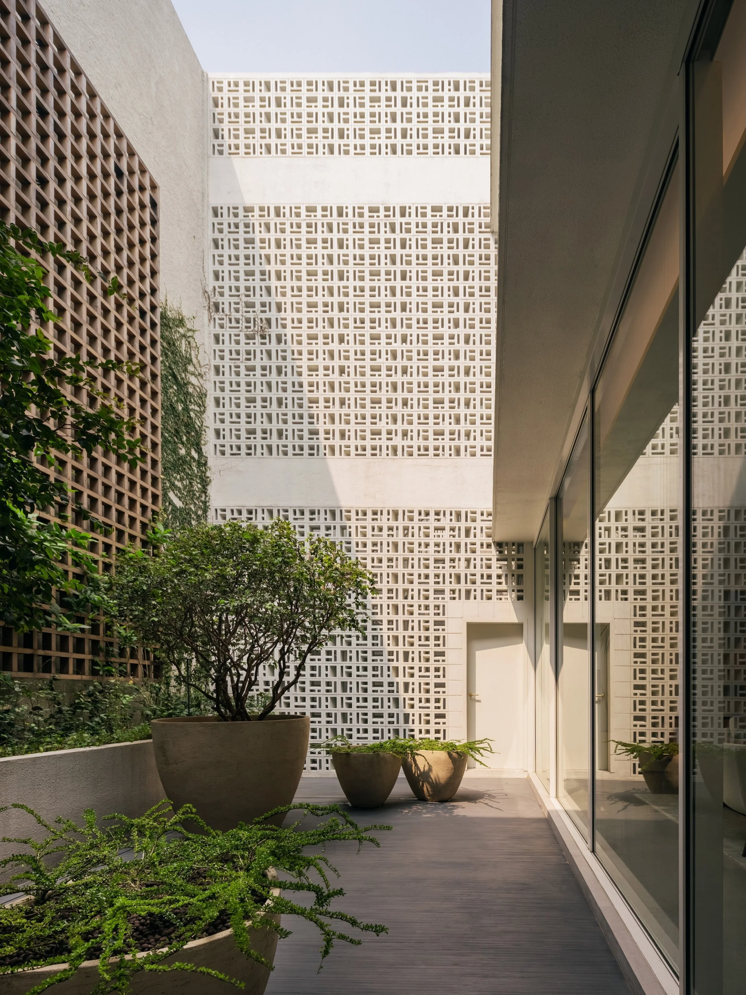 Jakarta Courtyard House

The rear courtyard uses the same concrete block as the facade to conceal the service staircase.
A gridded timber trellis with climbing plants mirrors the block design.

Photography: @kungphotograph 
Landscape: @thishumidhouse