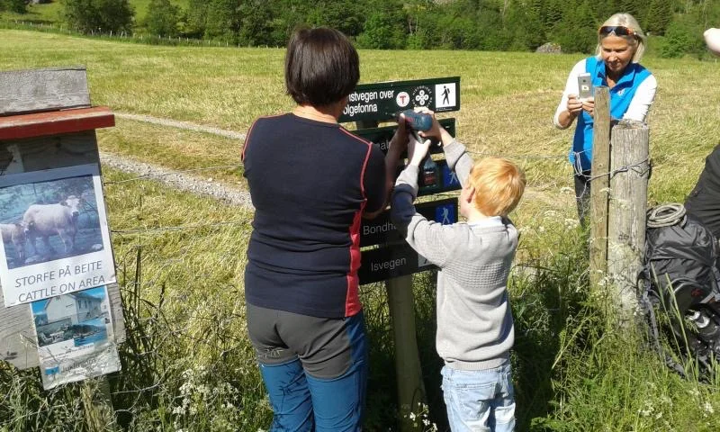 Leiar i Kvinnherad Turlag, Anne Kari Enes saman med Emil Gausvik hang opp vegvisarskiltet. Styreleiar i DNT, Berit Kjøll følgjer begeistra med på monteringa.