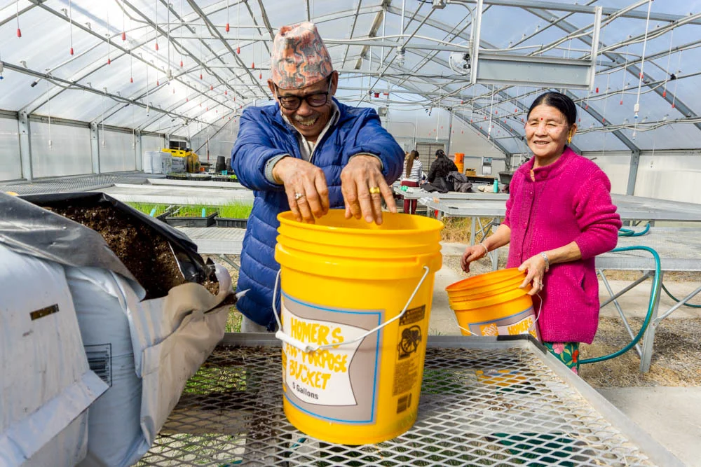Lal Subba, Growing Together farmer, mixing potting soil in the Nashville State Community College greenhouse.