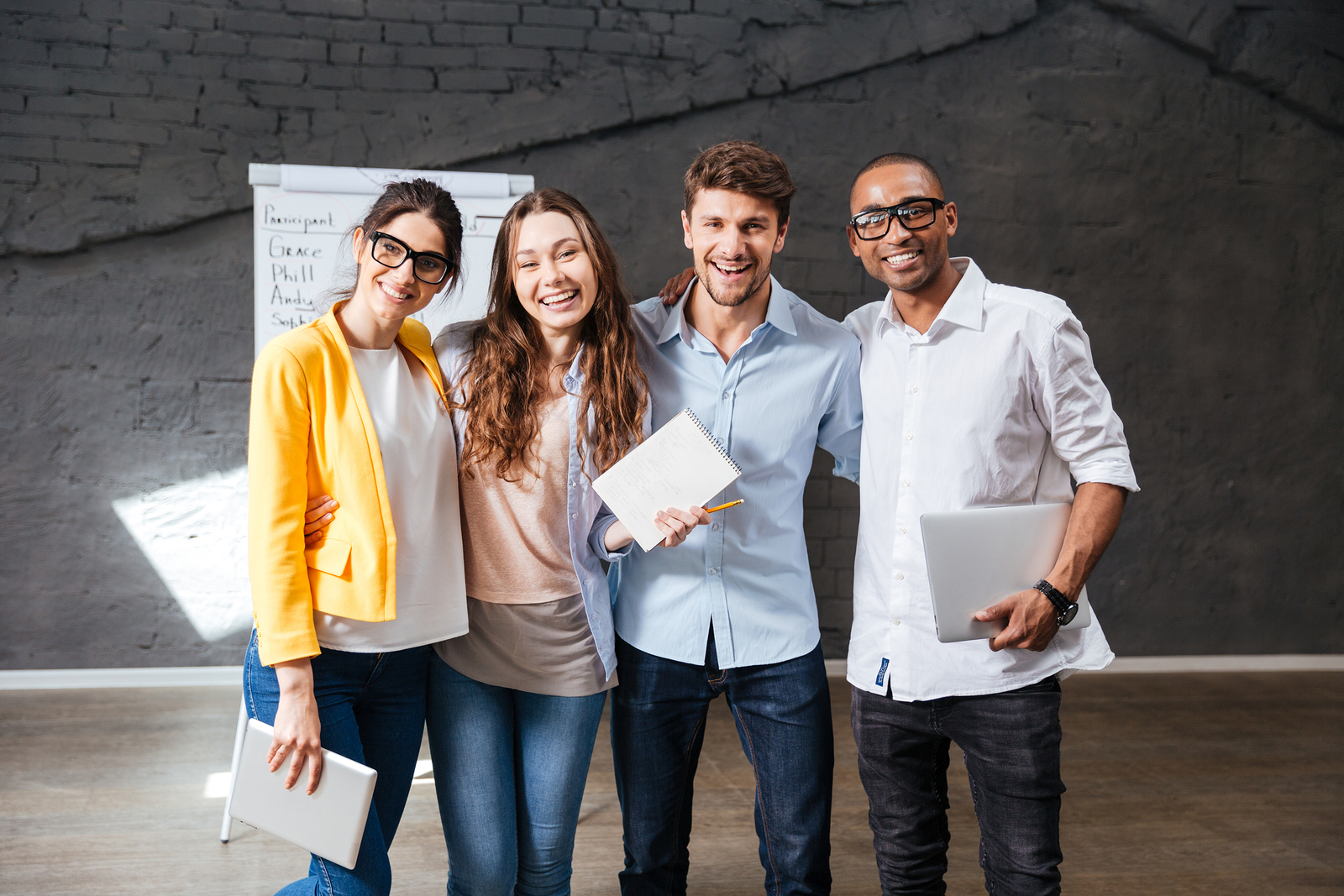 Multiethnic group of happy young business people holding tablet
