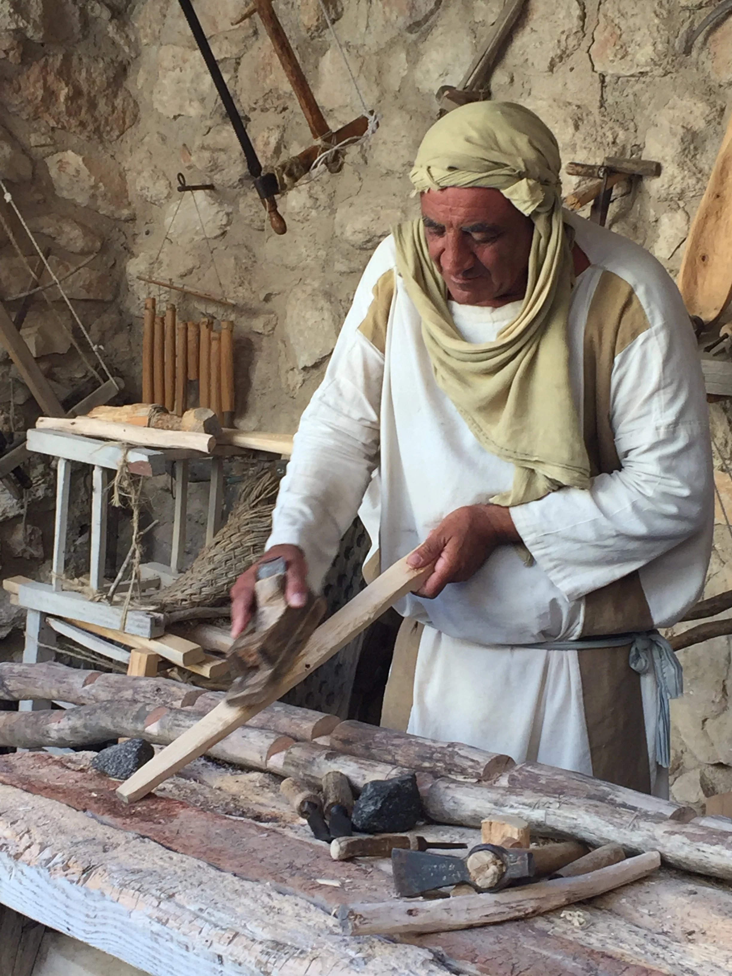 "Joseph" planing the rung of a ladder he was making using tools from the first century.
