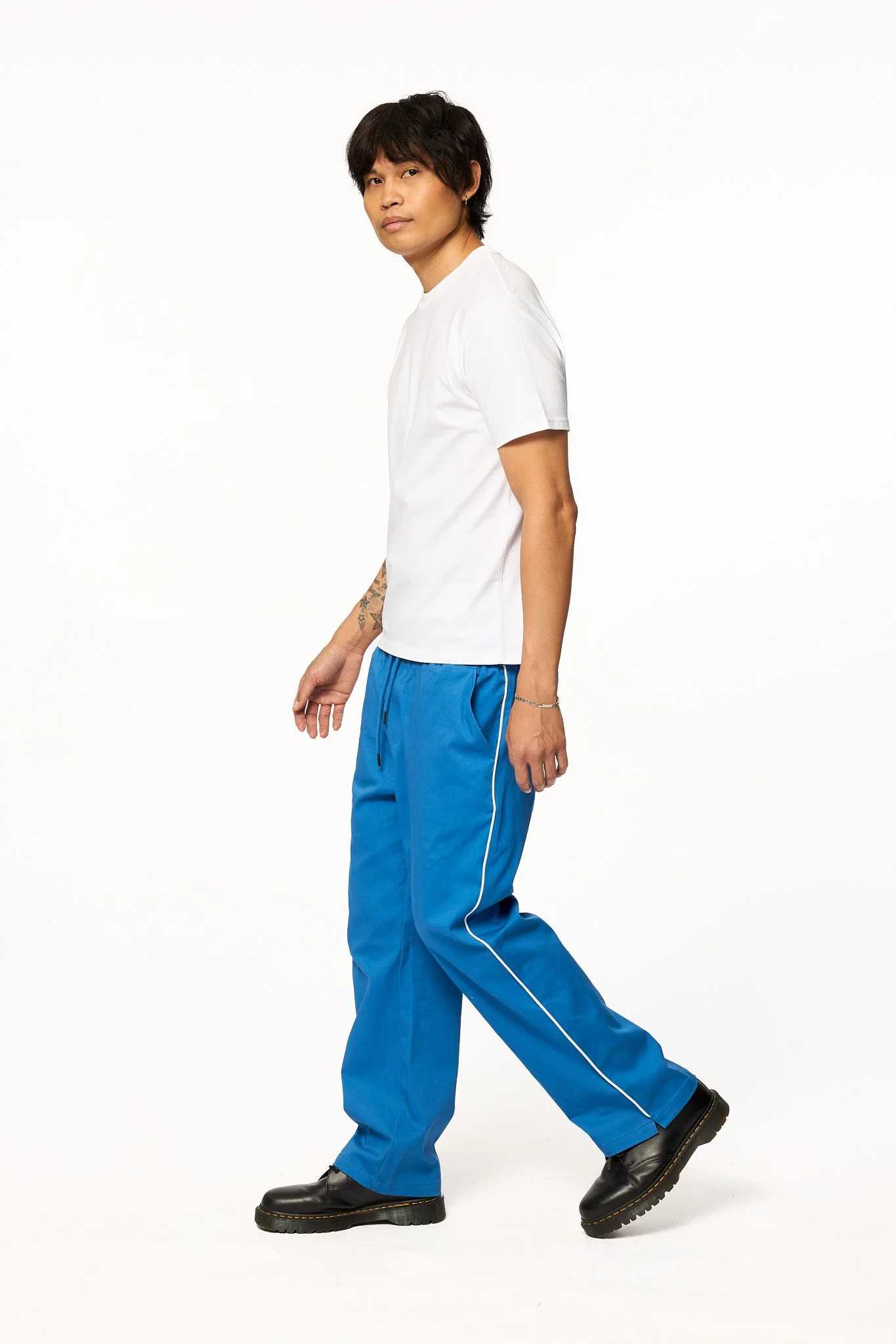 Royal blue piped pants by The SellOut full body walking view showing relaxed fit and white side piping