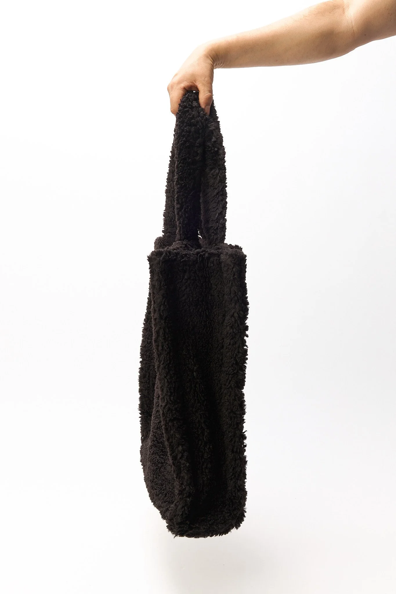 Black sherpa tote bag side view showing shape and strap length