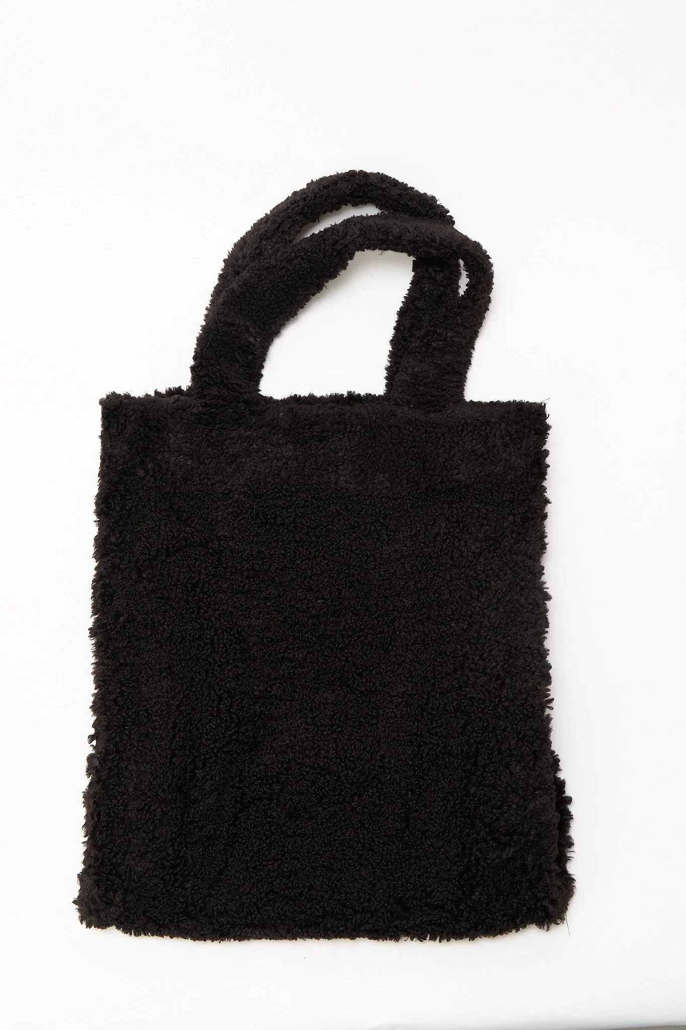 Black sherpa tote bag close-up showing soft fleece texture and material detail
