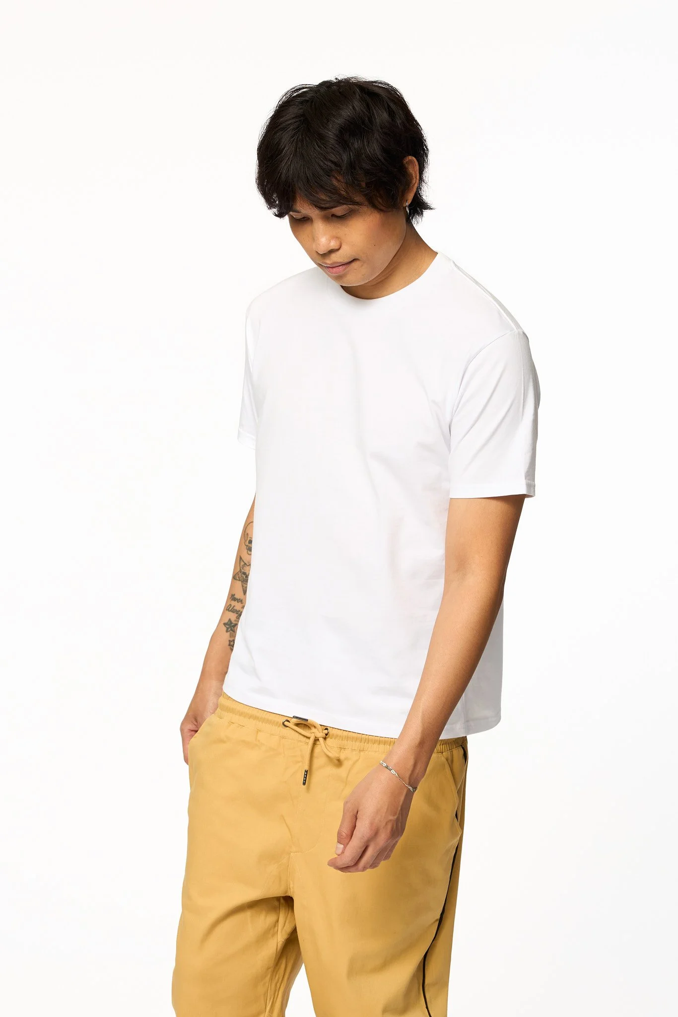 Model wearing The SellOut Heavyweight Short Cut Tee in white shown in an angled front view with a heavyweight cotton fit and slightly shorter body.