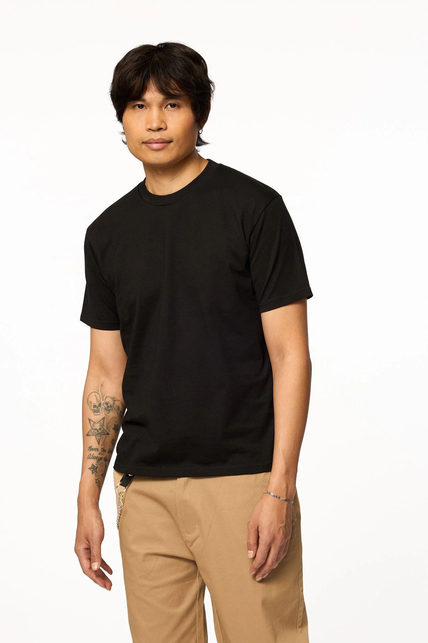 Model wearing The SellOut Heavyweight Short Cut Tee in black shown in an angled front view with a heavyweight cotton fit and slightly shorter body.