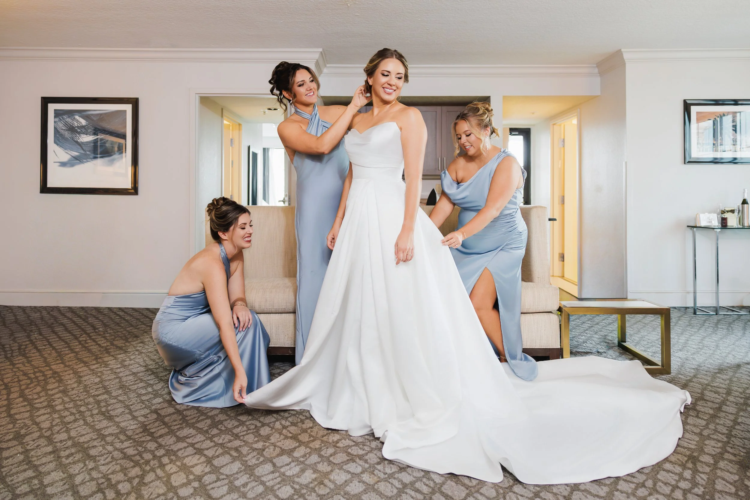 Bridesmaids adjusting the bride's dress and helping her out with preperations for her wedding. Orlando wedding.