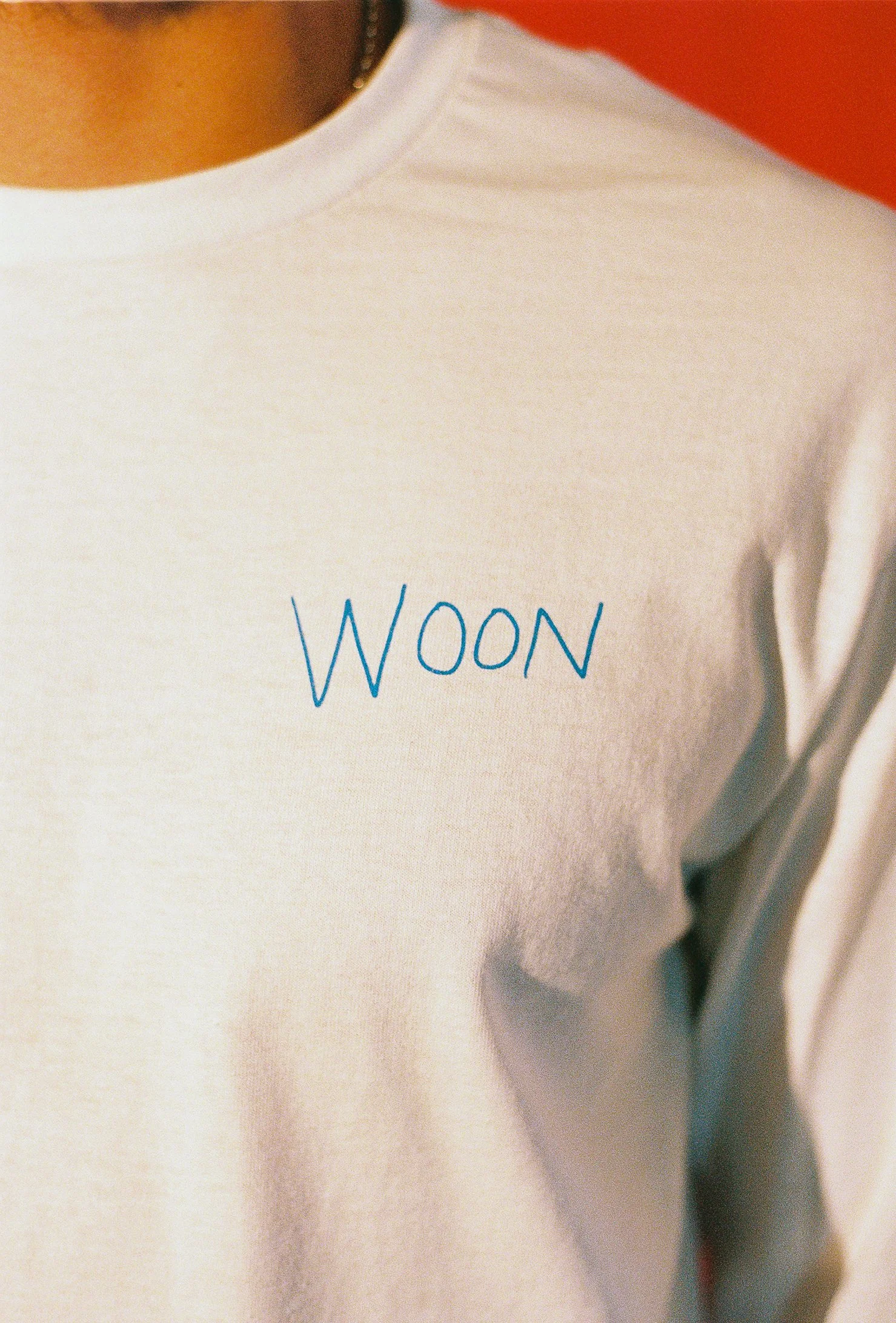 The front of a white long sleeve shirt with Woon written in blue