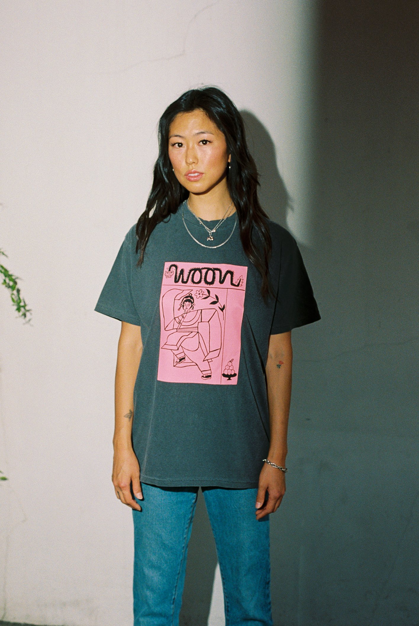 Someone wearing a faded black t-shirt with pink artwork
