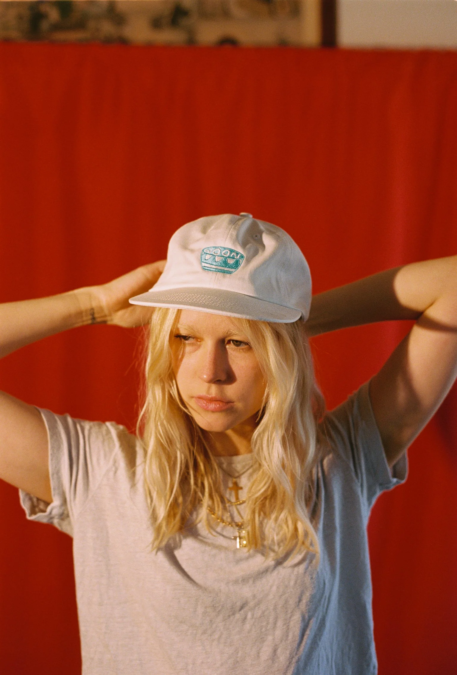 A person wearing a white flat bill cap with blue artwork