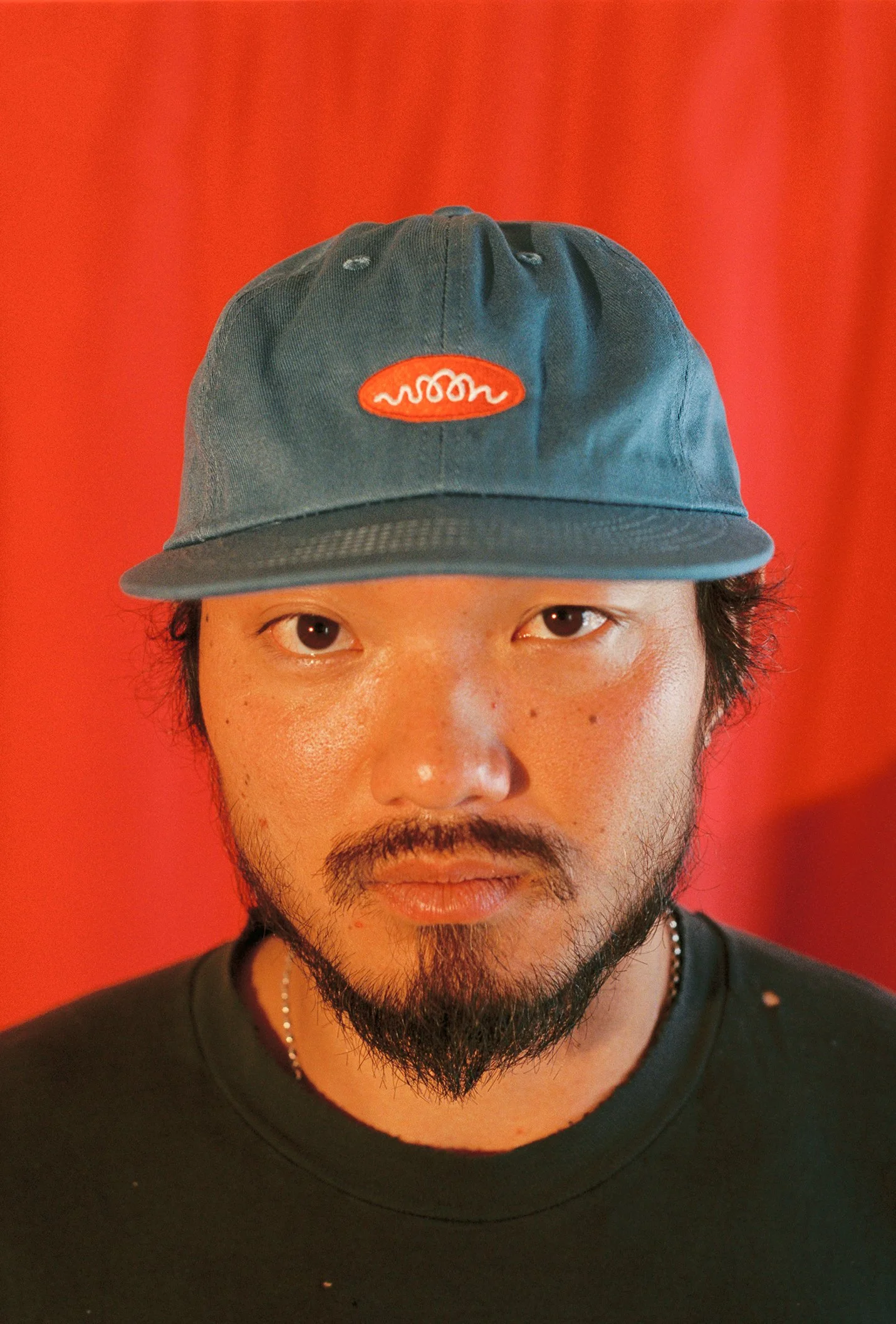 A person wearing a blue flat bill cap with Woon logo
