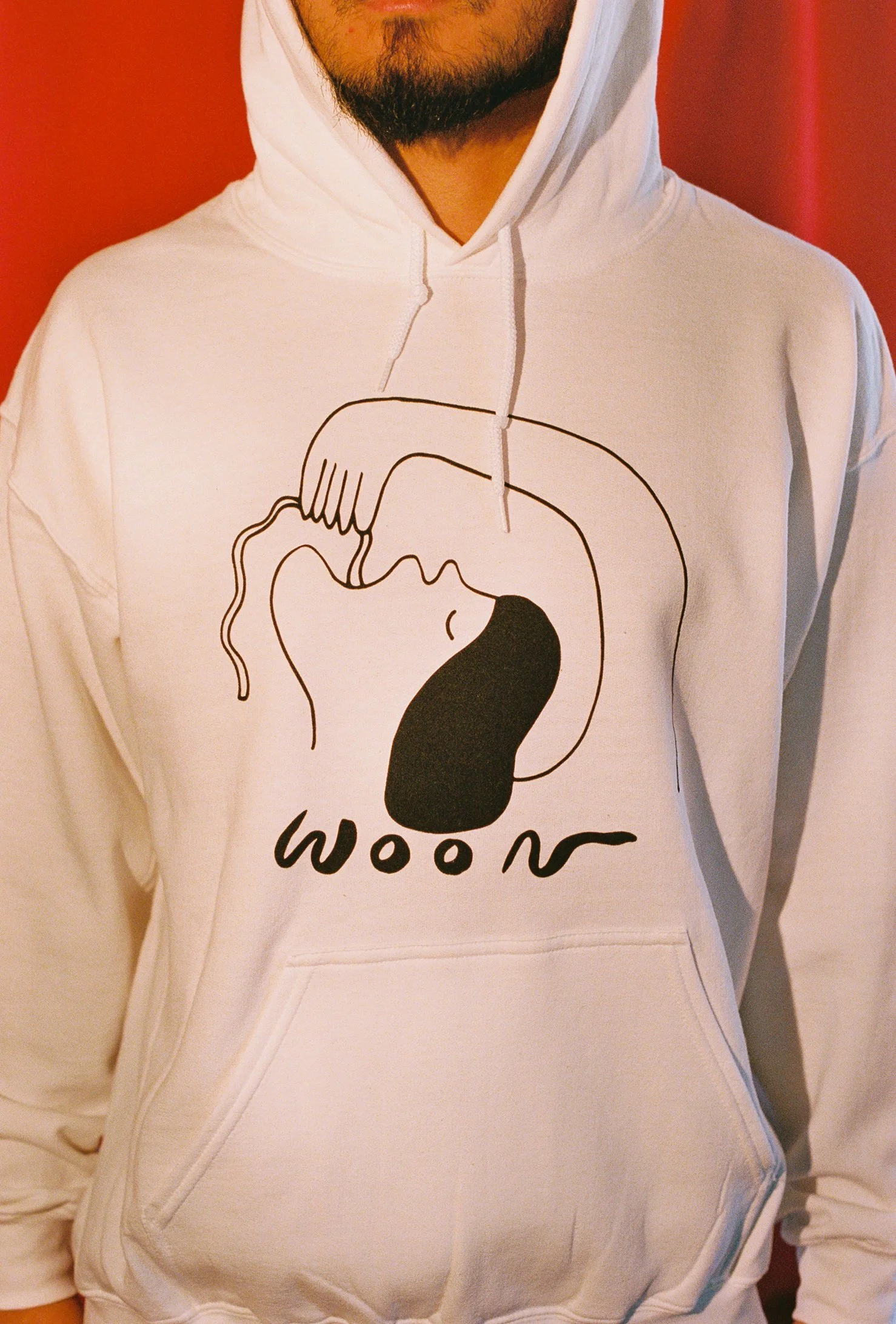 A person wearing a white hoodie with black artwork of a person eating a noodle