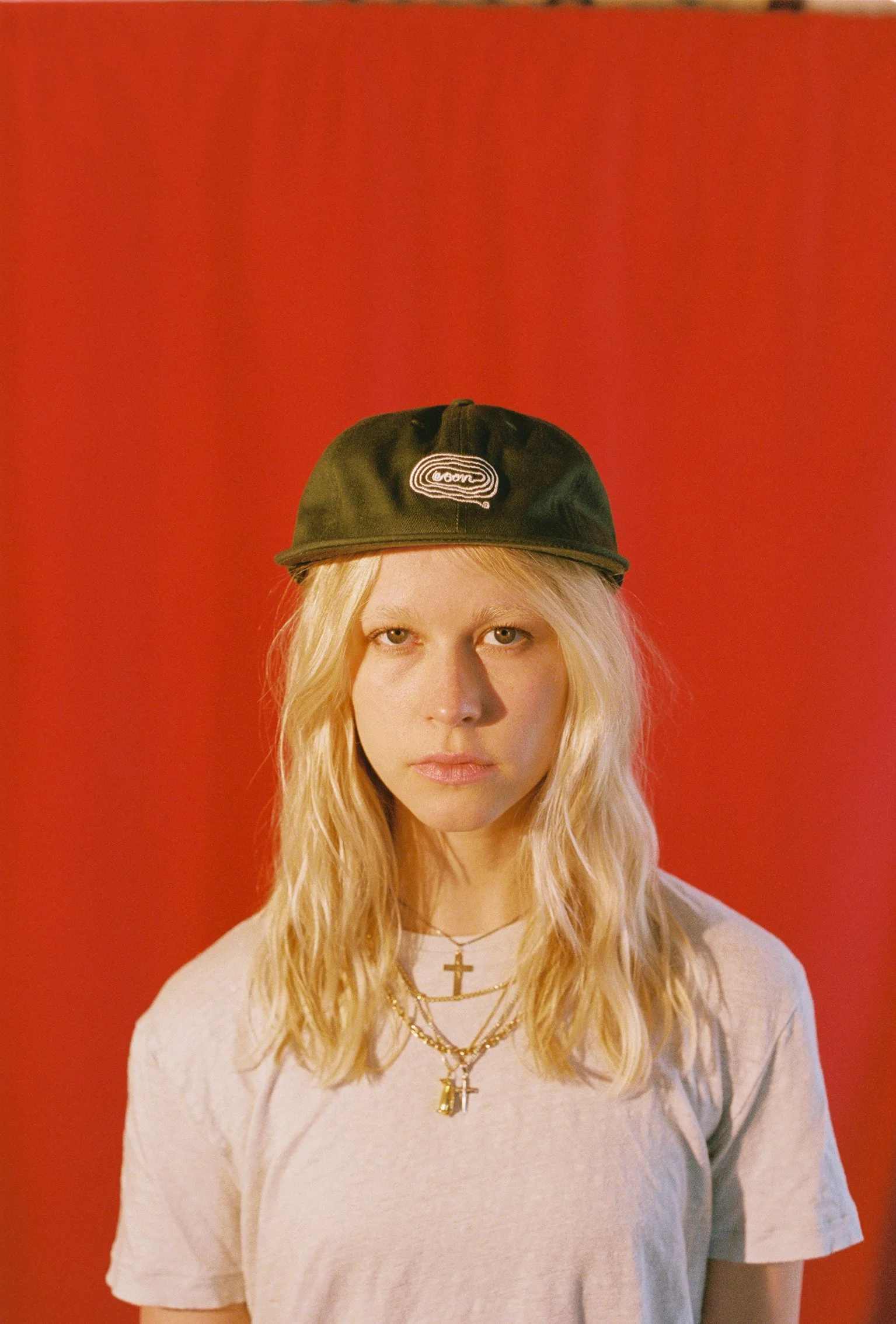 A person wearing a black flat bill cap with white artwork of noodles