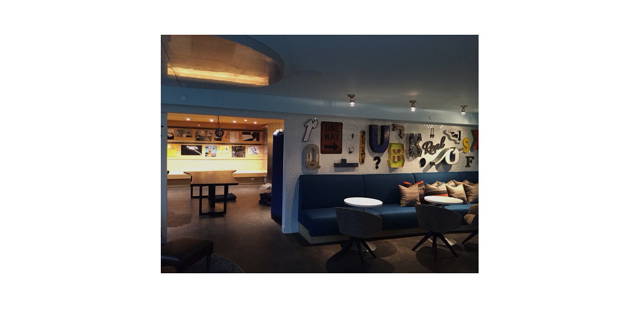 Vintage signage wall (foreground) and gallery wall with custom industrial hanging system (background). 