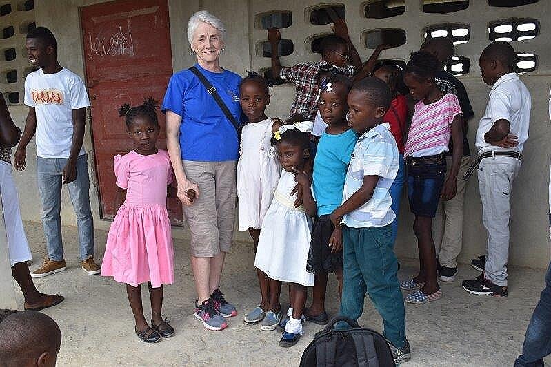 Jeanine holds hands with children at school.