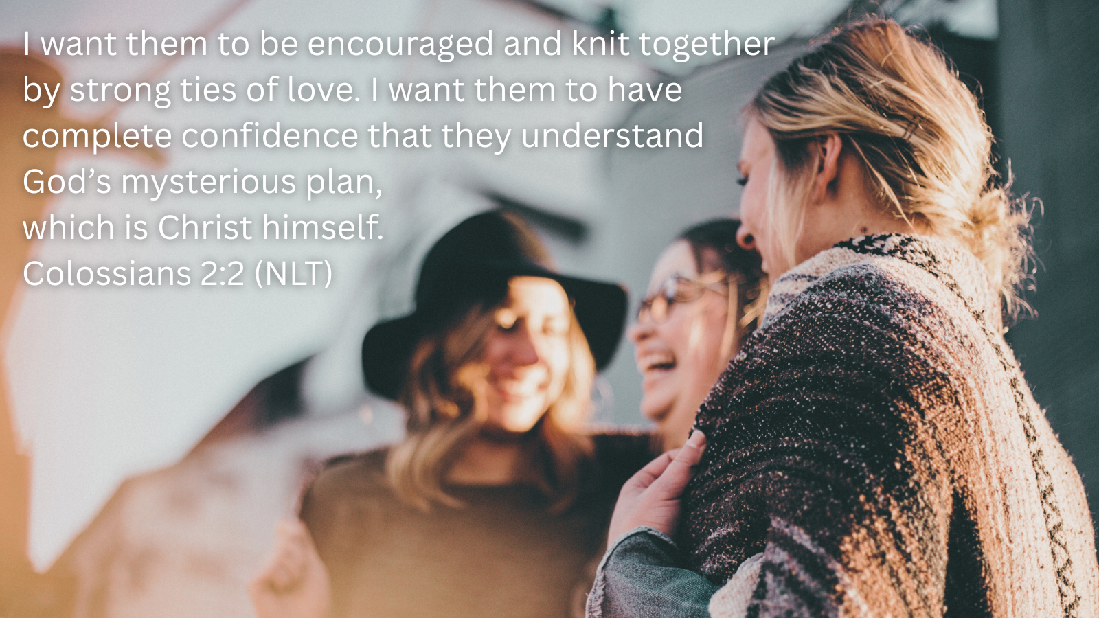 three women laughing outside with a quotation of Colossians 2:2, NLT