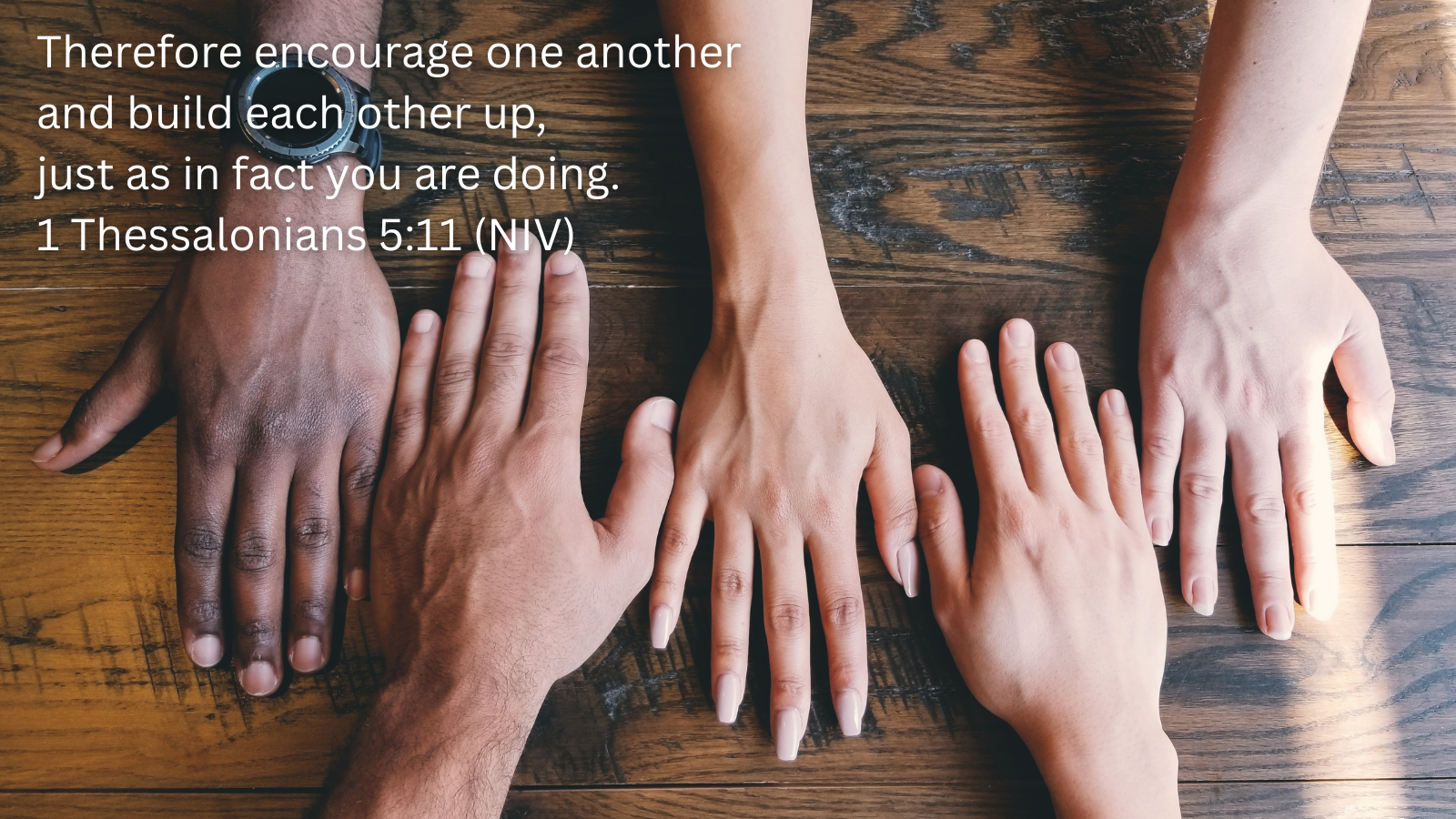 hands from different ethnicities placed palm down on a wooden table and a quotation of 1 Thessalonians 5:11, NIV
