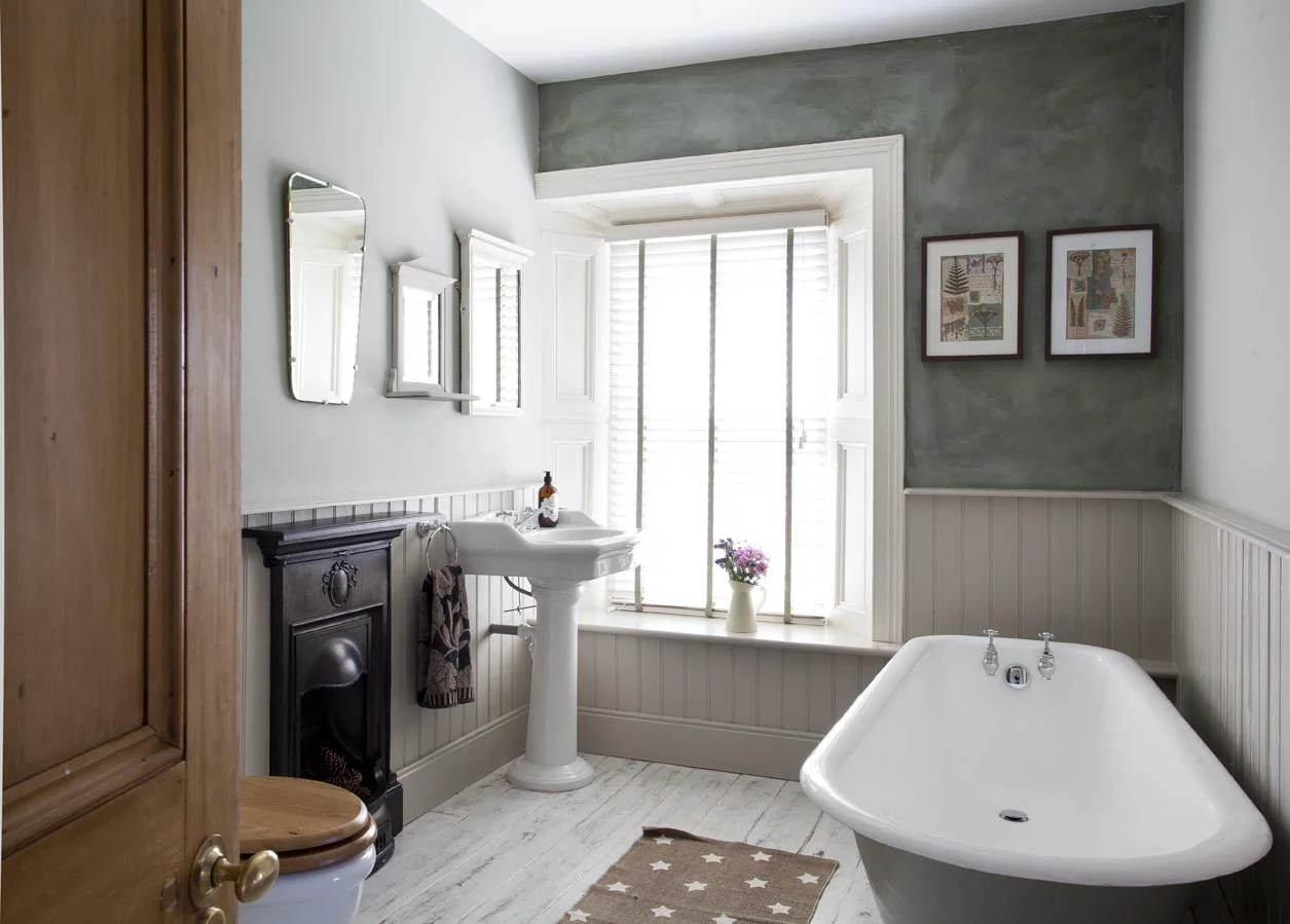 The original roll top, cast iron bath was brought back to prime condition and given a tasteful backdrop of painted tongue and groove panelling.