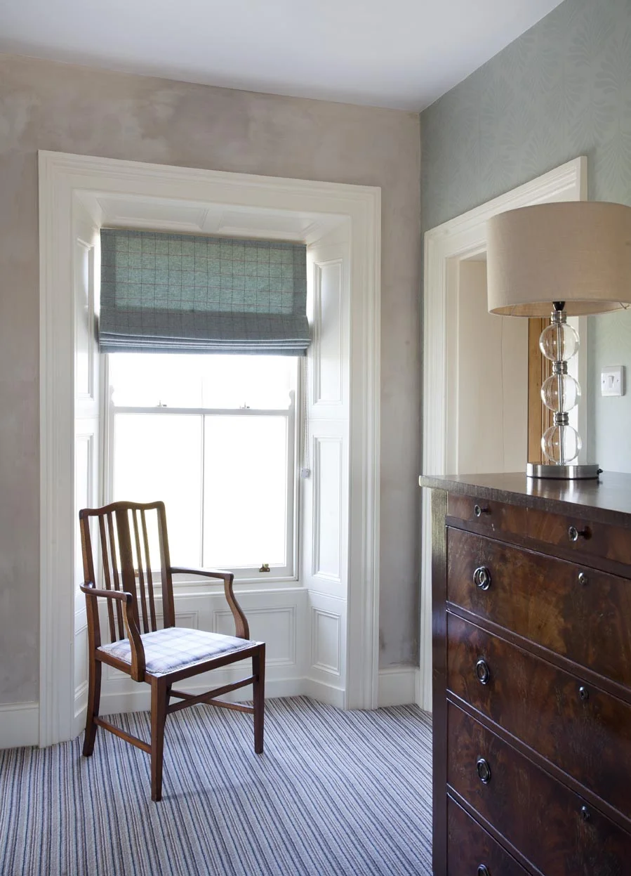 The rich wood tones of the antique furniture contrast beautifully with the painted wood panelling around the windows.