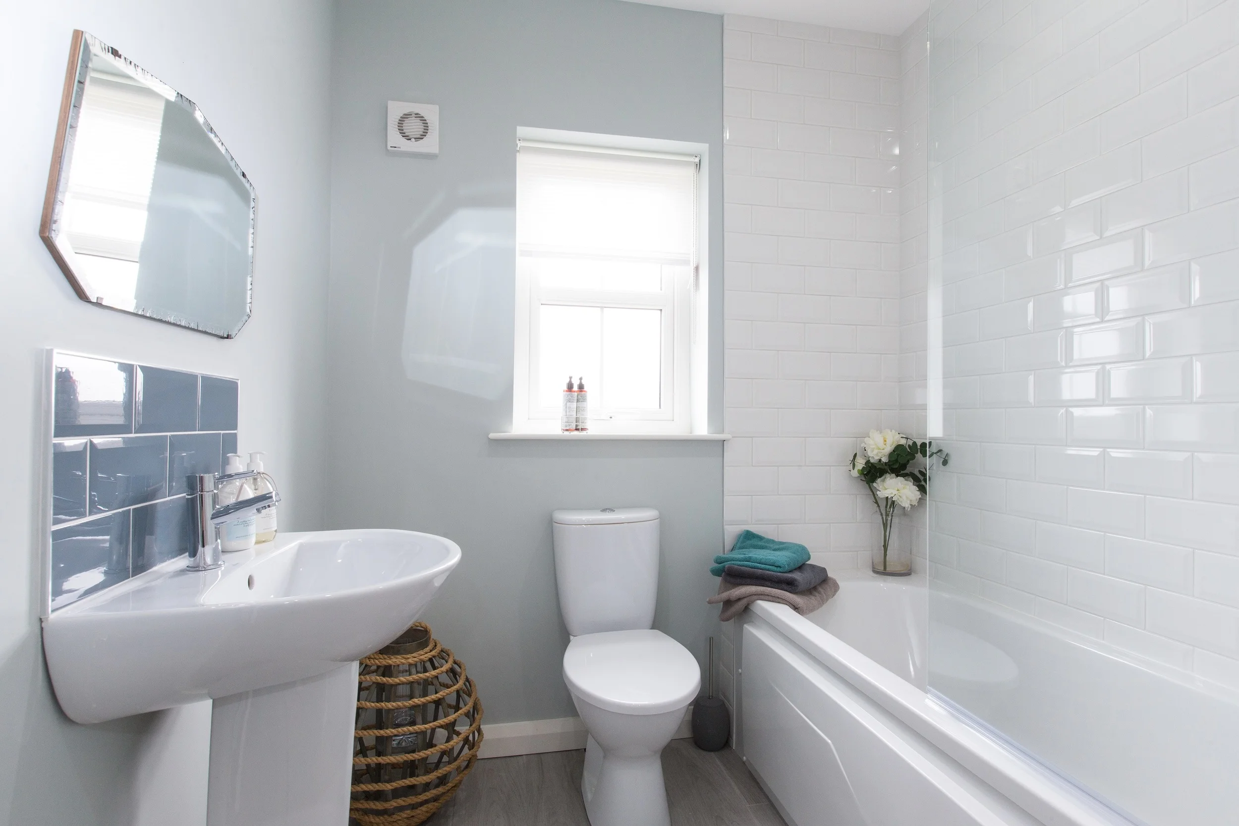 The main bathroom repeats the master en suite metro tiles and adds a touch of glamour with retro style bevel-edged mirror.